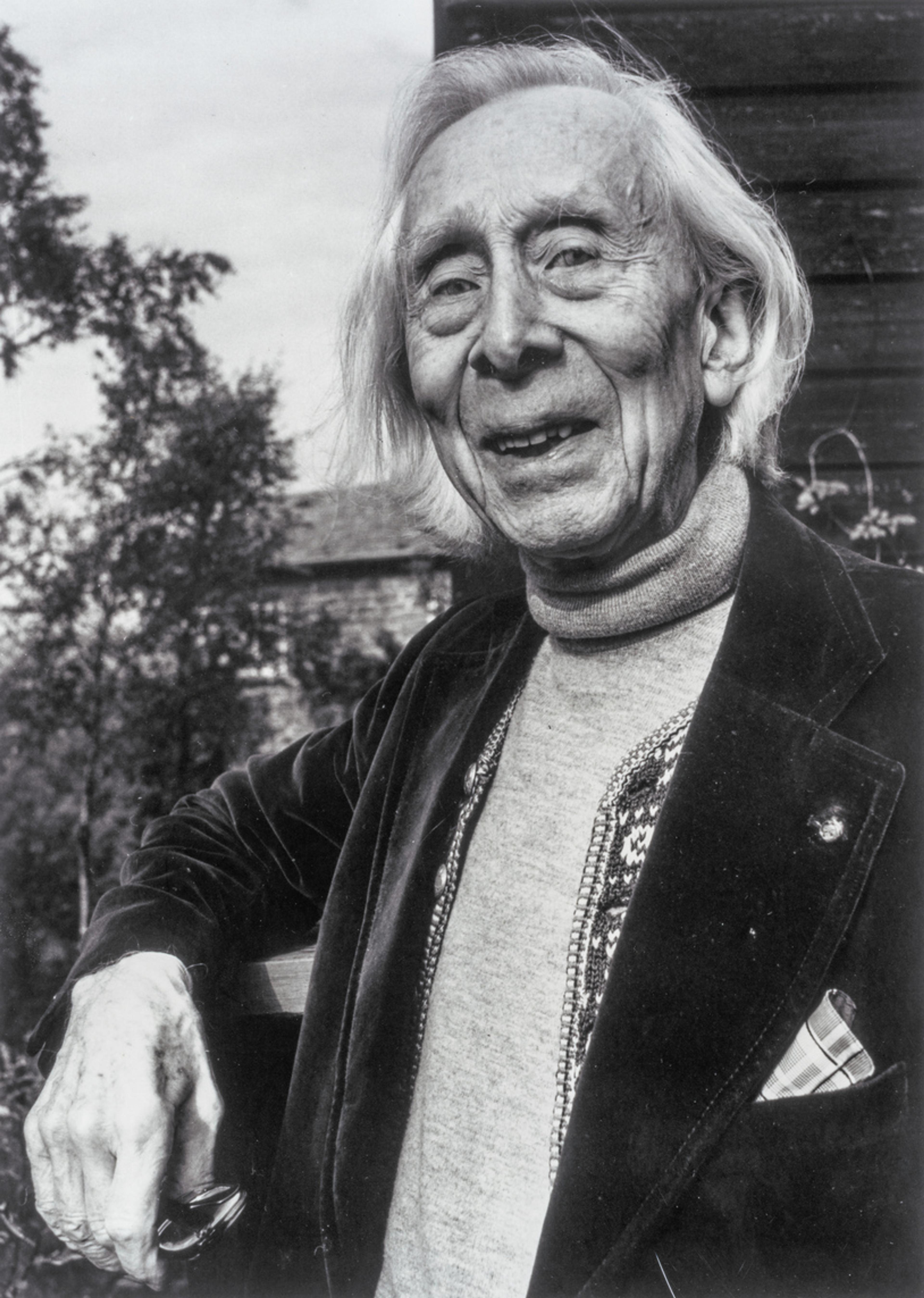 Portrett av Harald Sæverud i sort-hvitt. Han lener seg mot et rekkverk og smiler mot kamera.