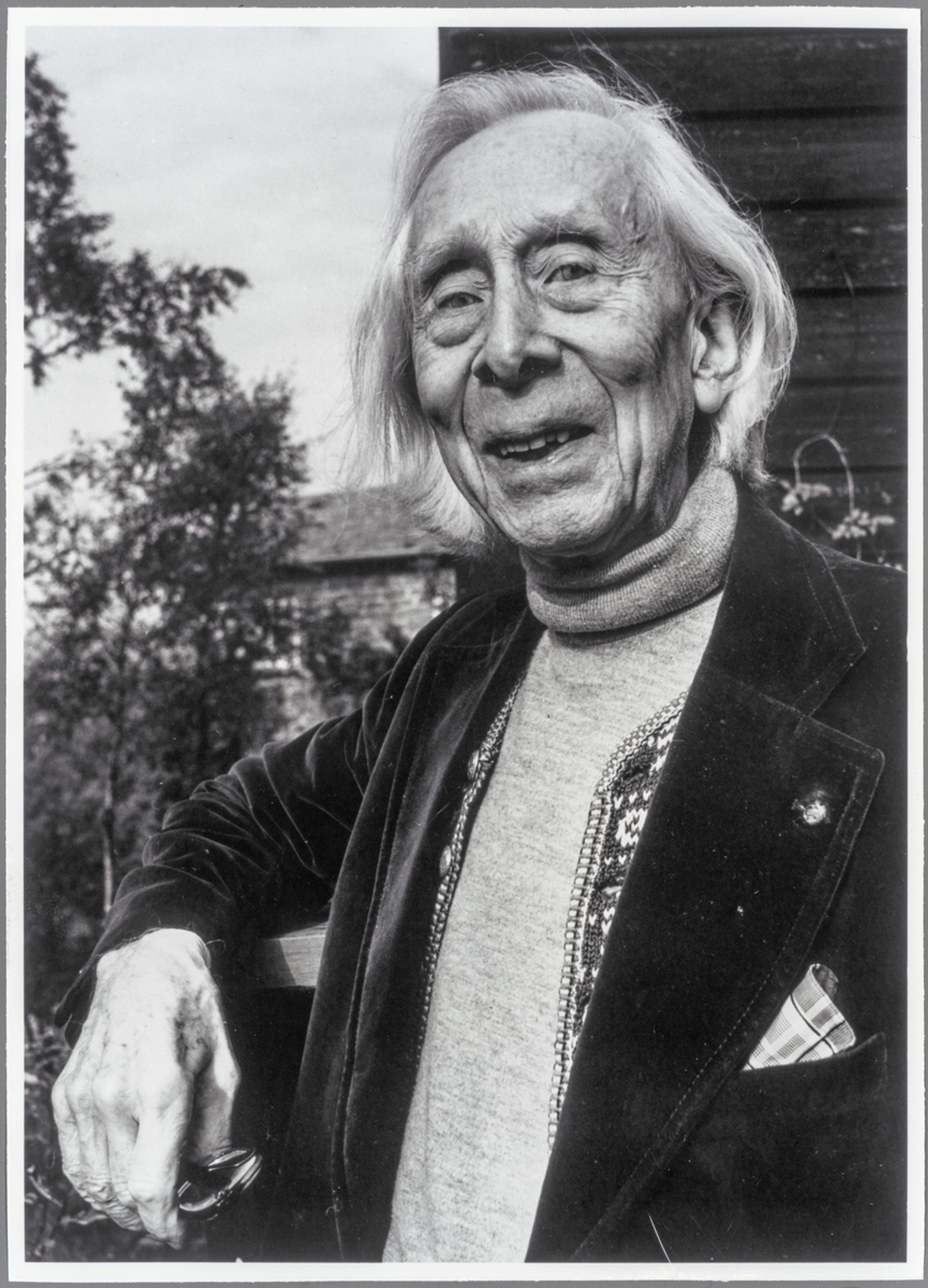Portrett av Harald Sæverud i sort-hvitt. Han lener seg mot et rekkverk og smiler mot kamera.