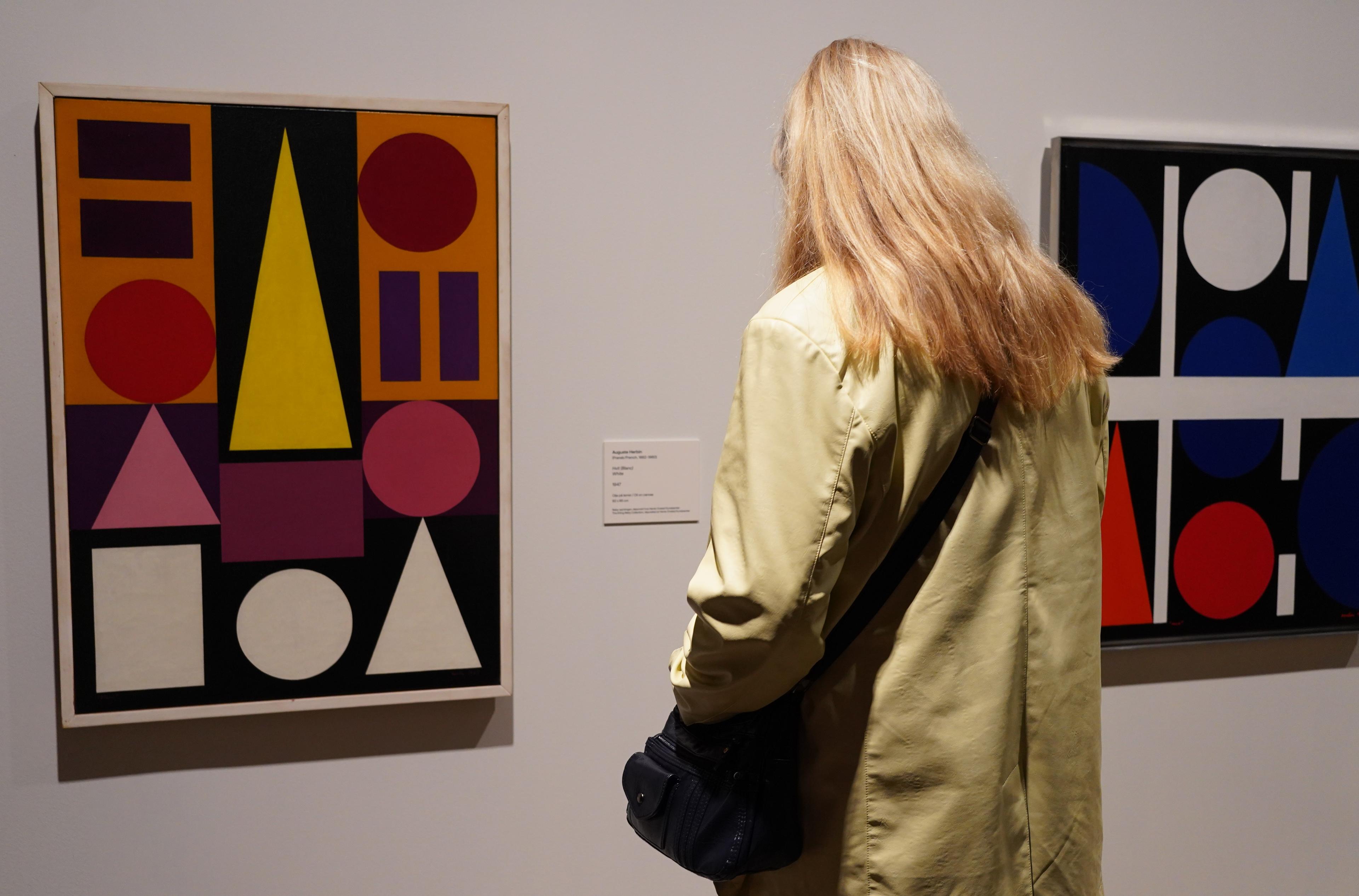 En person står foran to abstrakte fargerike malerier