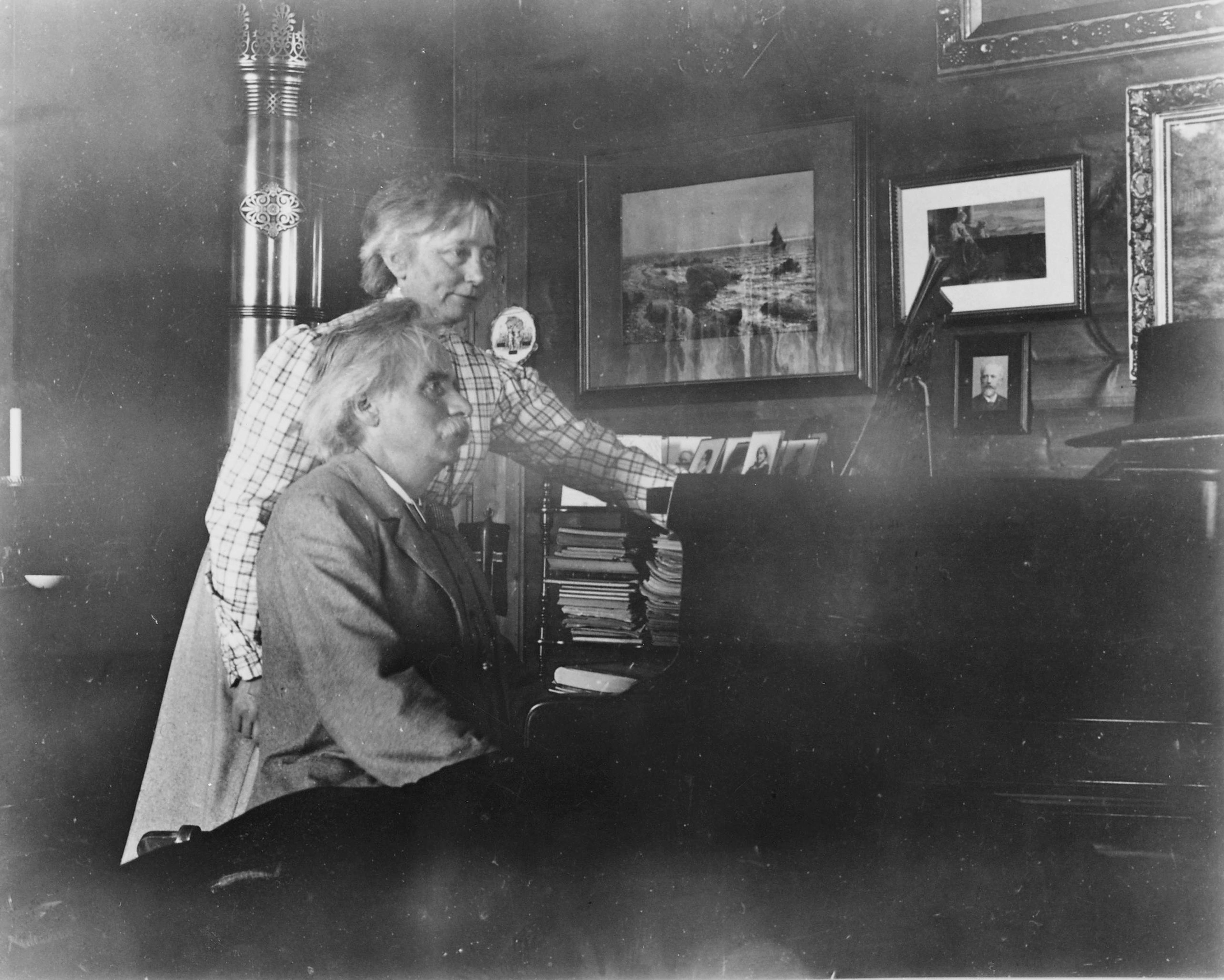 Fotografi av Nina og Edvard Grieg ved pianoet. 