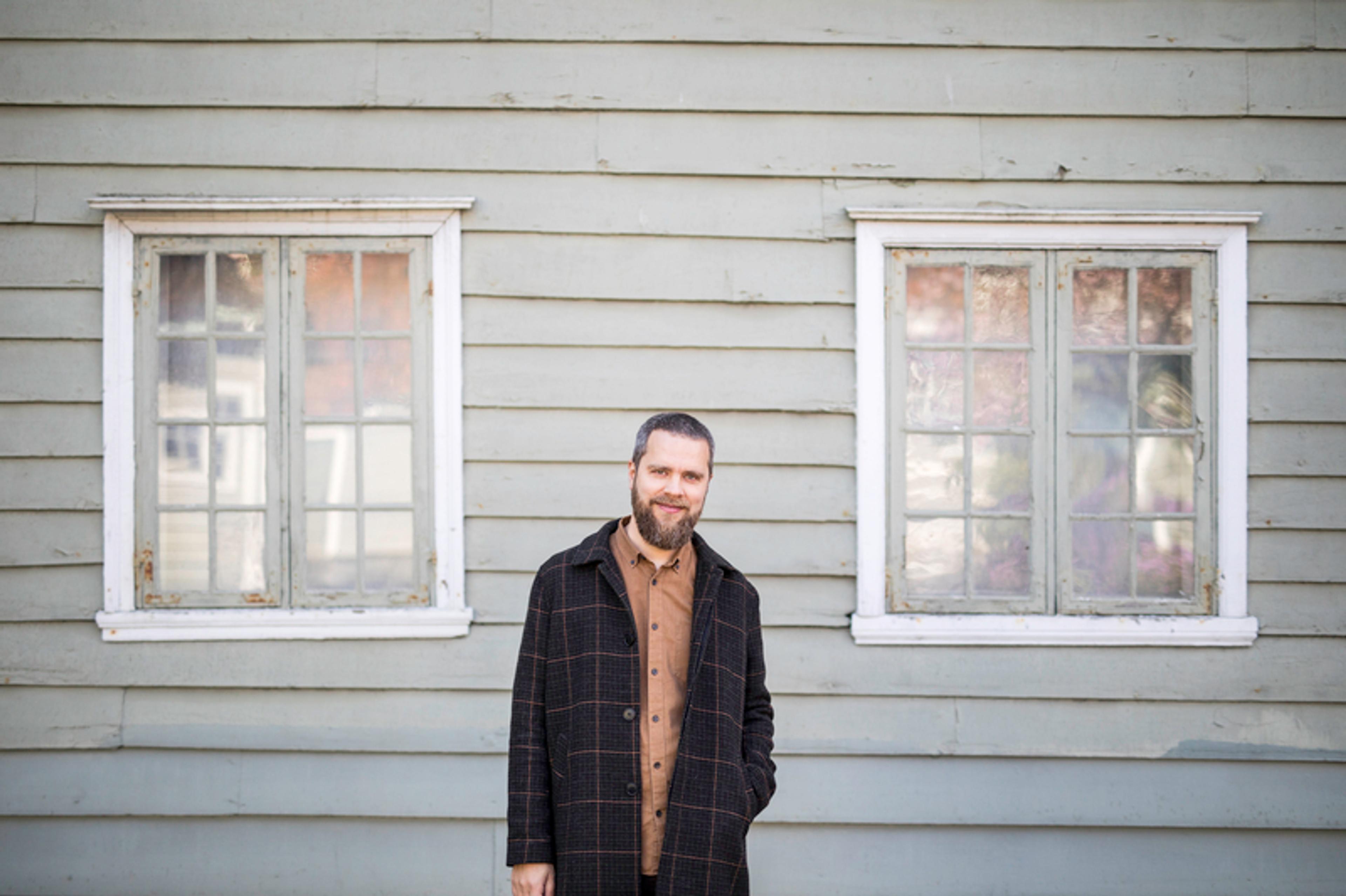 Komponisten Ørjan Matre står foran en lysgrønn vegg. Han ser i kamera og smiler.