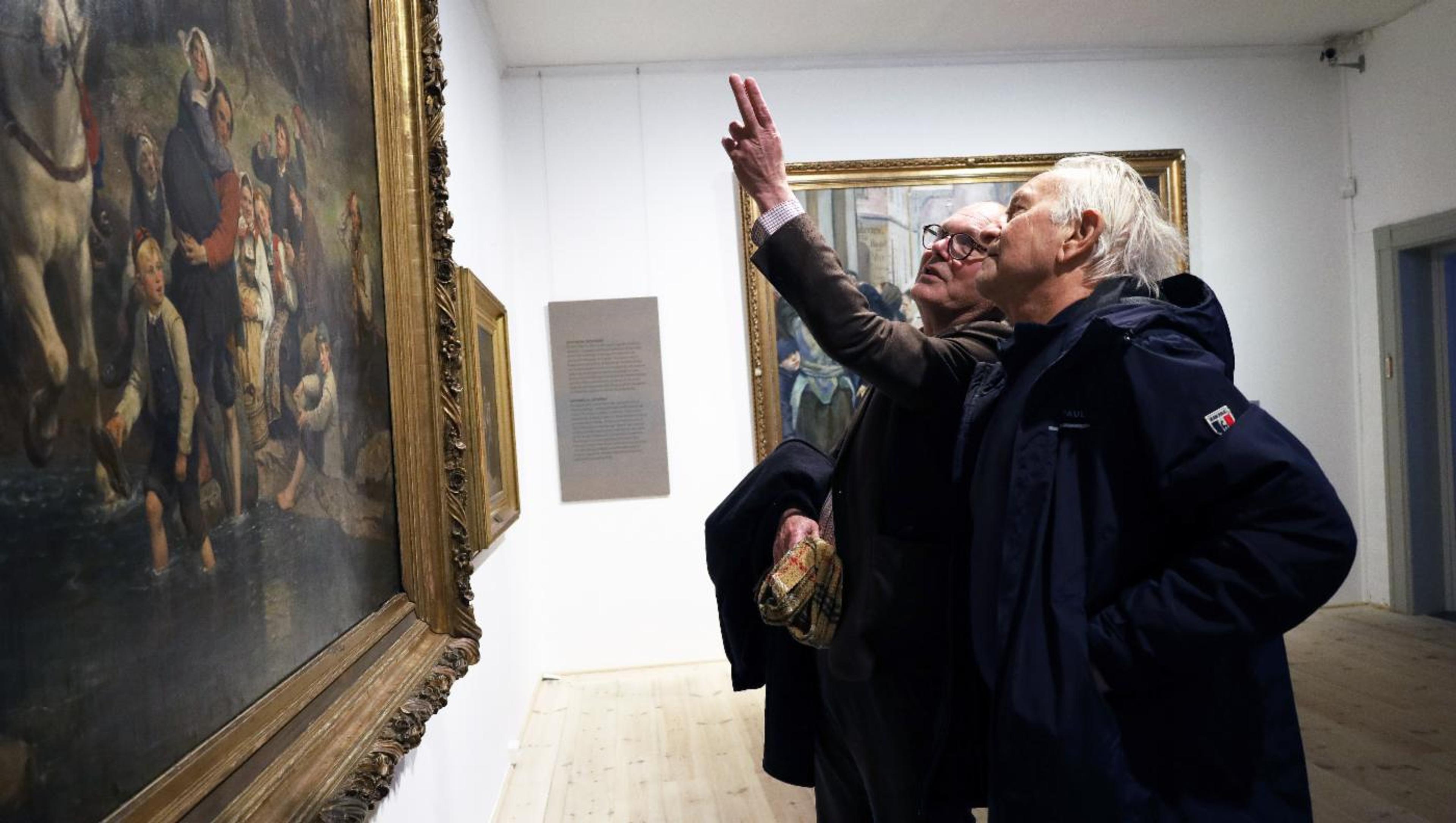 Et bilde av to menn som ser på kunst.