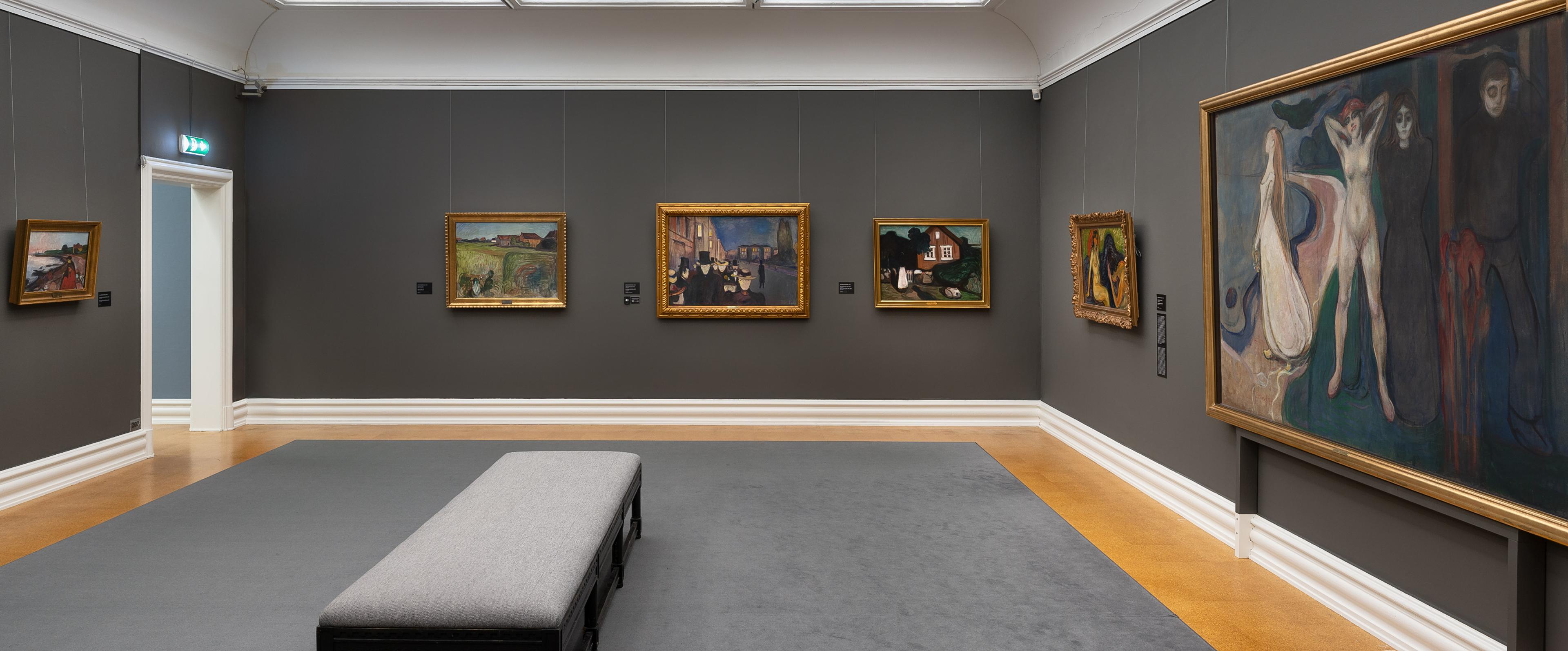 Et utstillingsrom med grå vegger, med malerier av Edvard Munch.