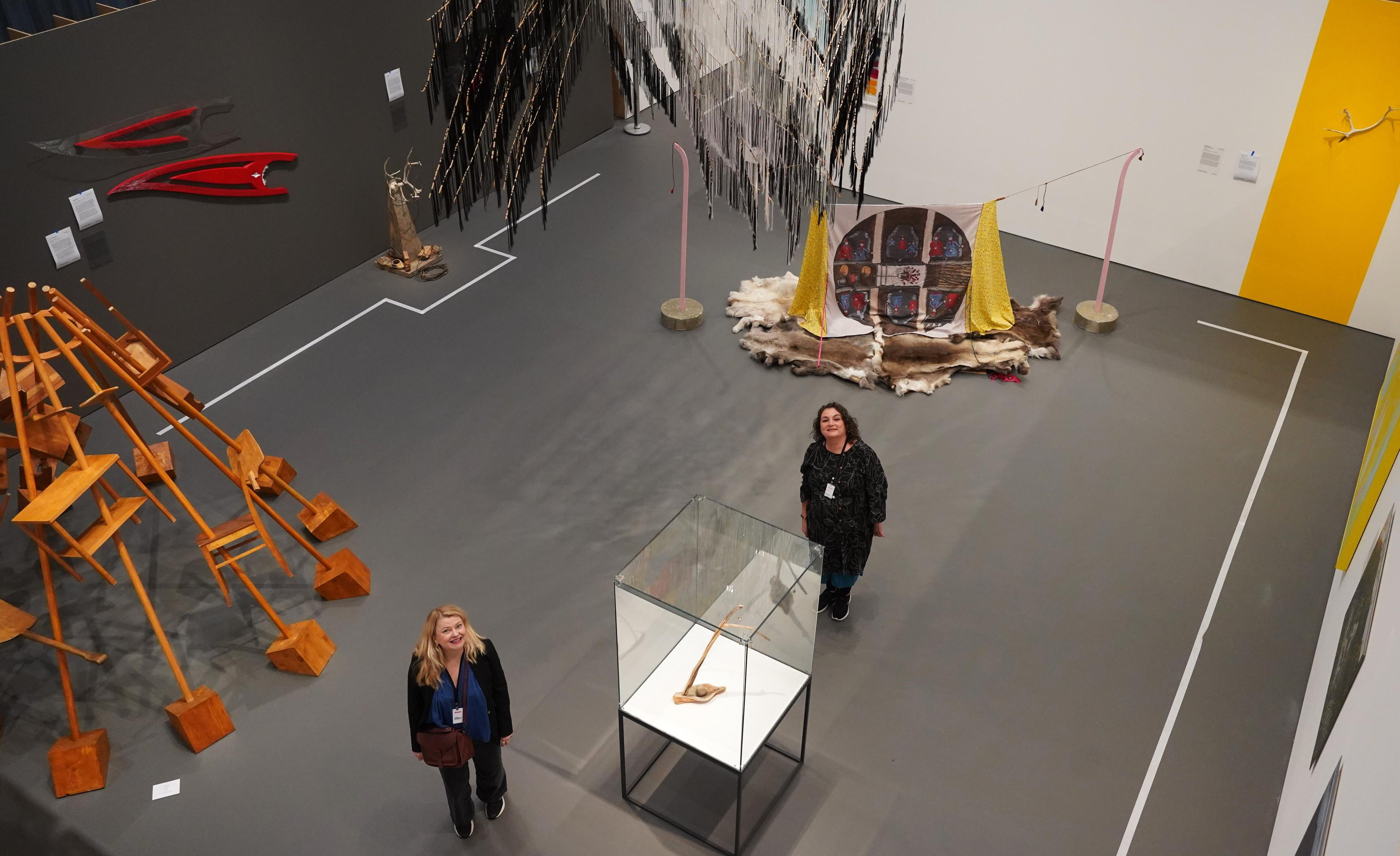 To kvinner i et stort utstillingslokale omgitt av samisk kunst og gjenstander