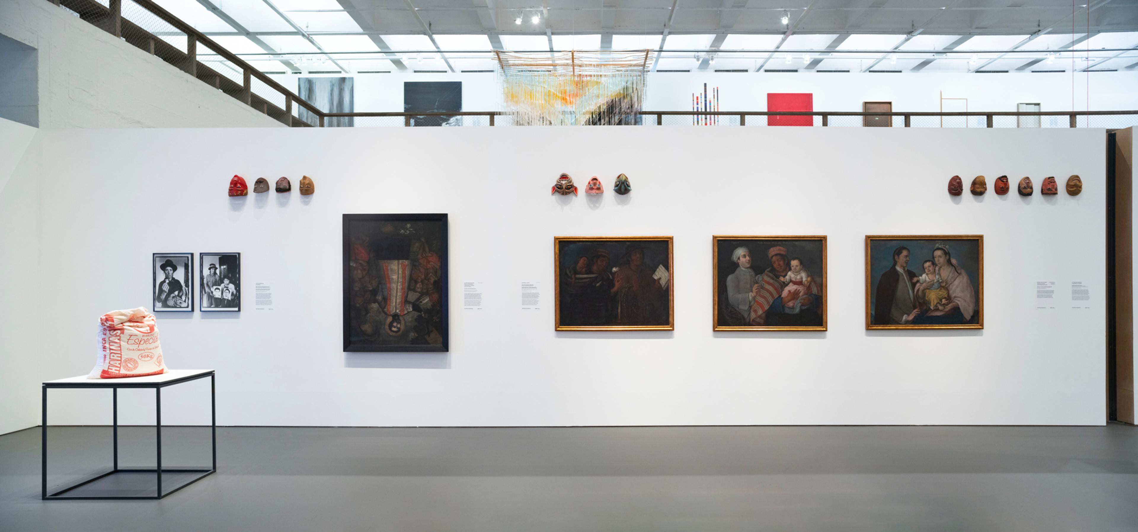 En rekke fargerike objekter og malerier i et utstillingsrom med en brun vegg