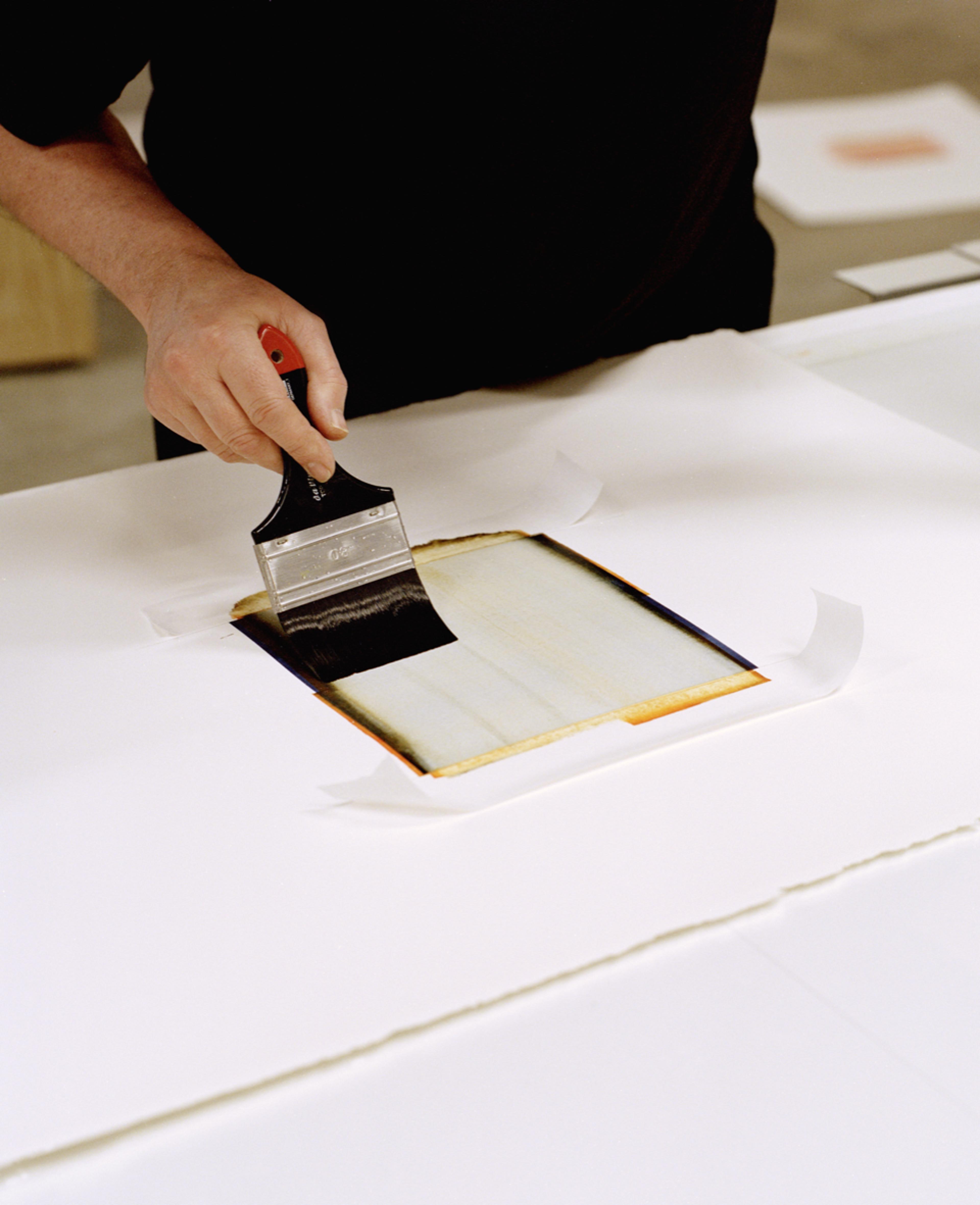 En hånd påfører maling på et ark