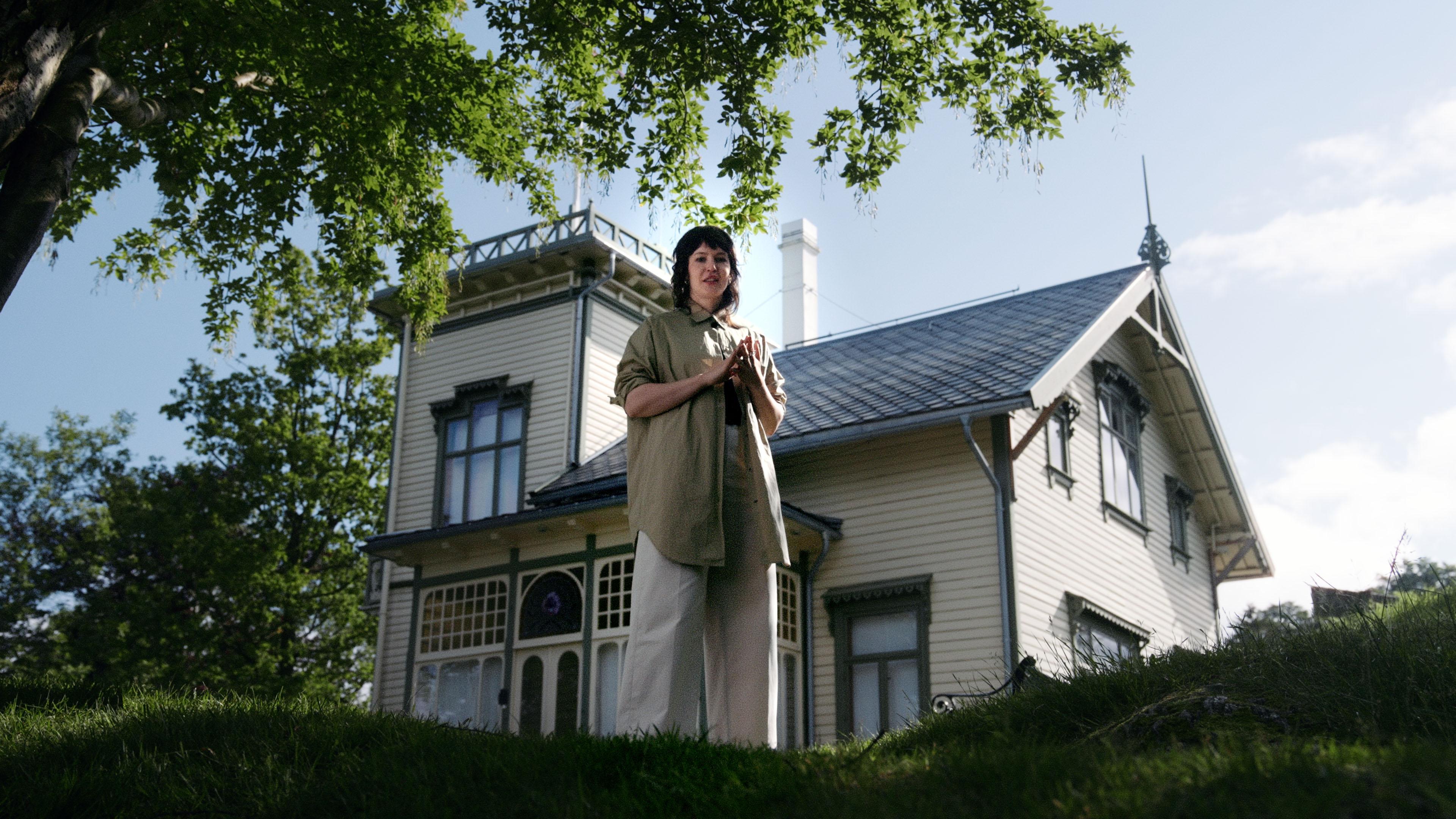 En kvinne står foran villaen på Troldhaugen