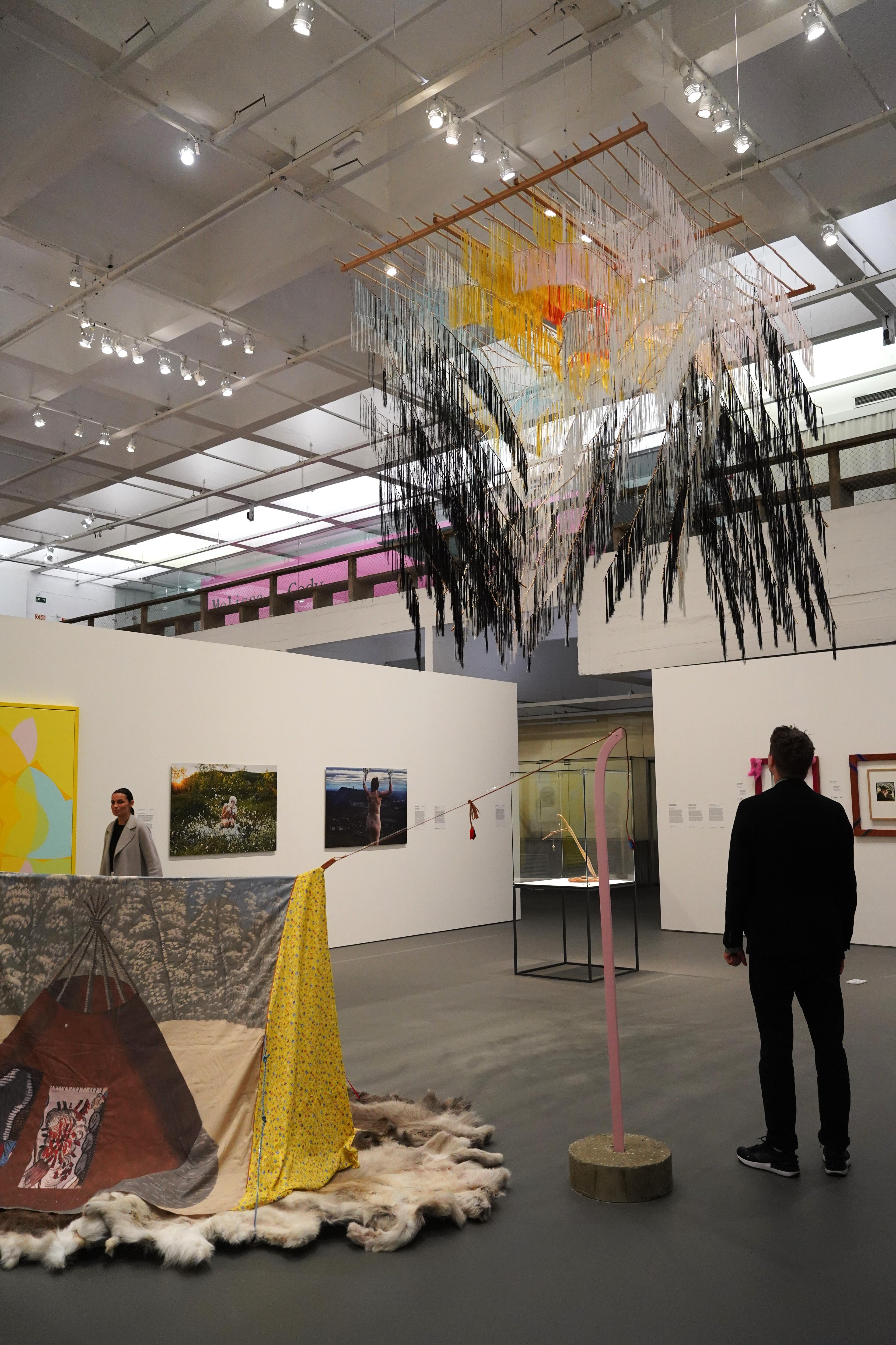 En person i et utstillingsrom med installasjoner og objekter i mange farger