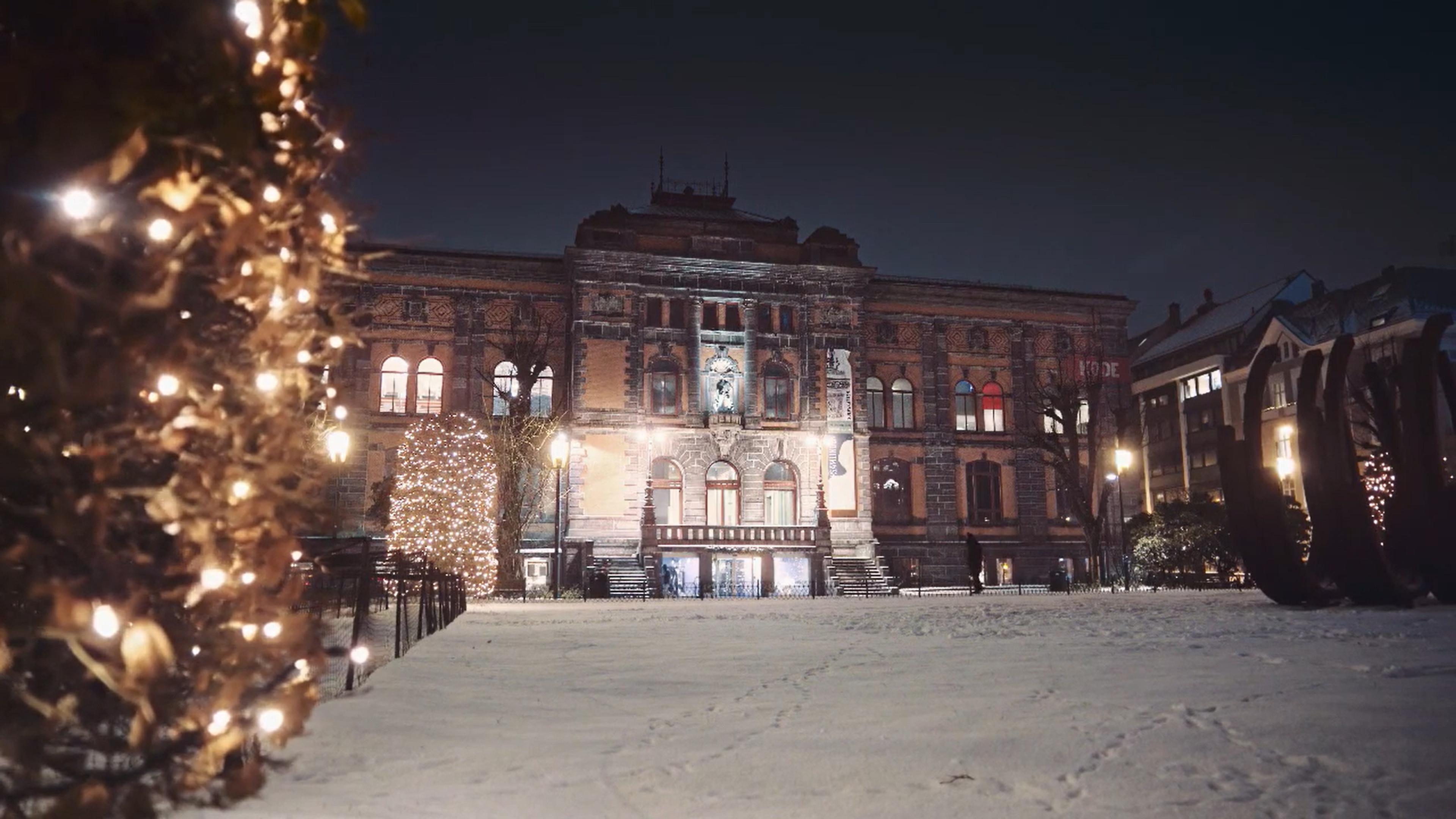 Foto av Permanenten museum i mørke med julelys og snø.