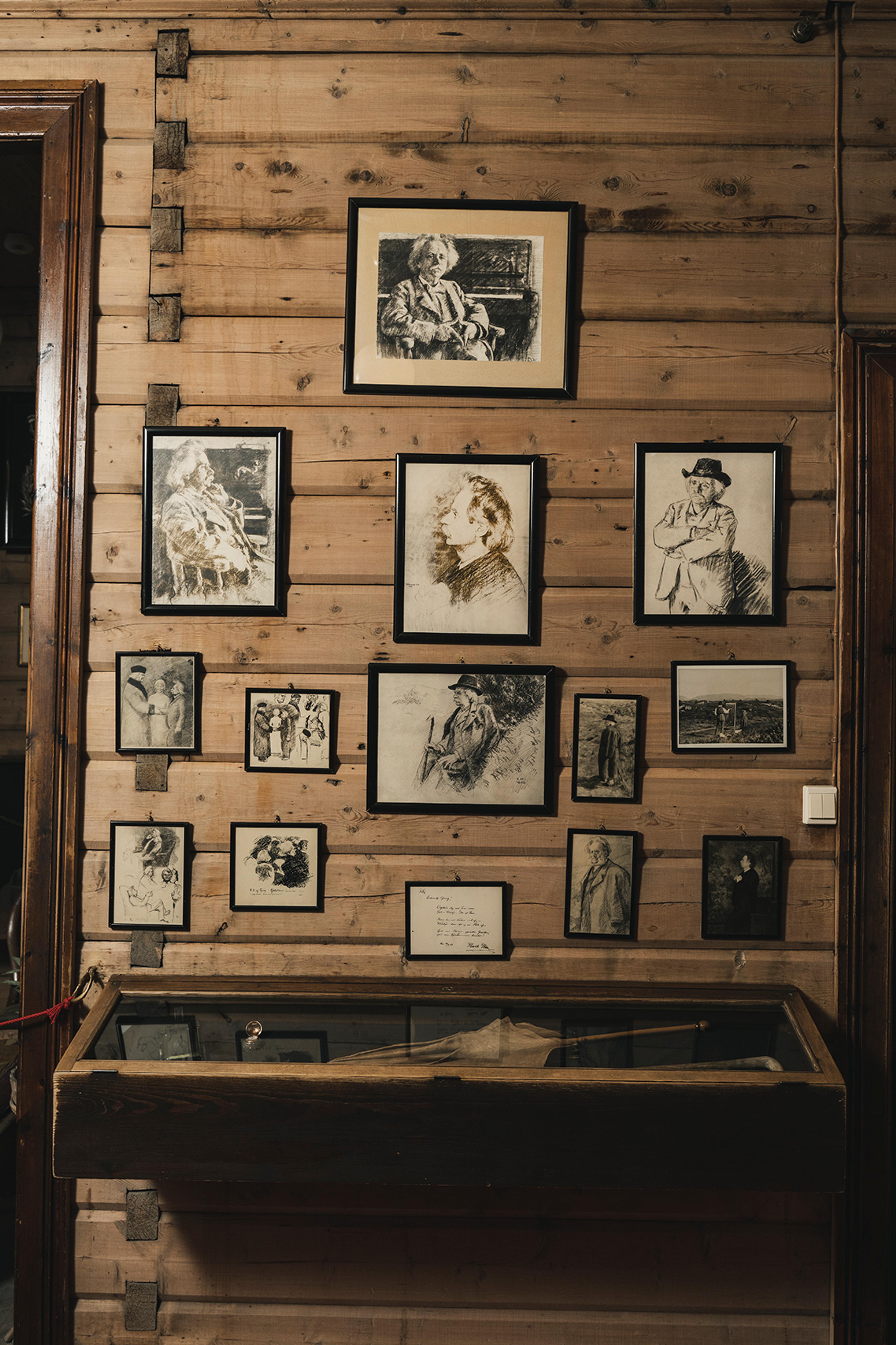 Fra minnerommet i Griegs villa, hvor vi ser en paraply i en monter og flere bilder på veggen