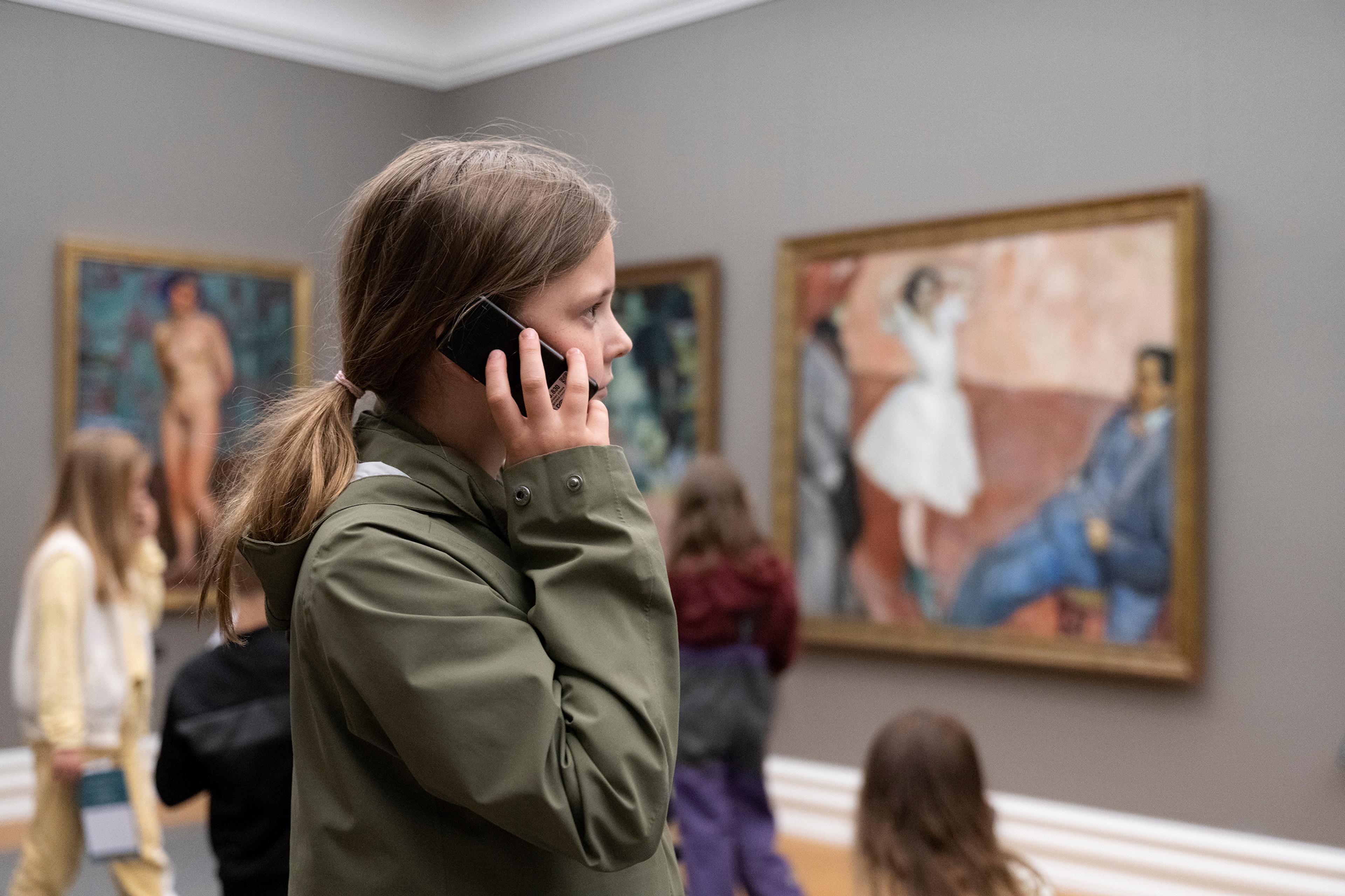 A young girl listening to an audioguide in the Rasmus Meyer museum.