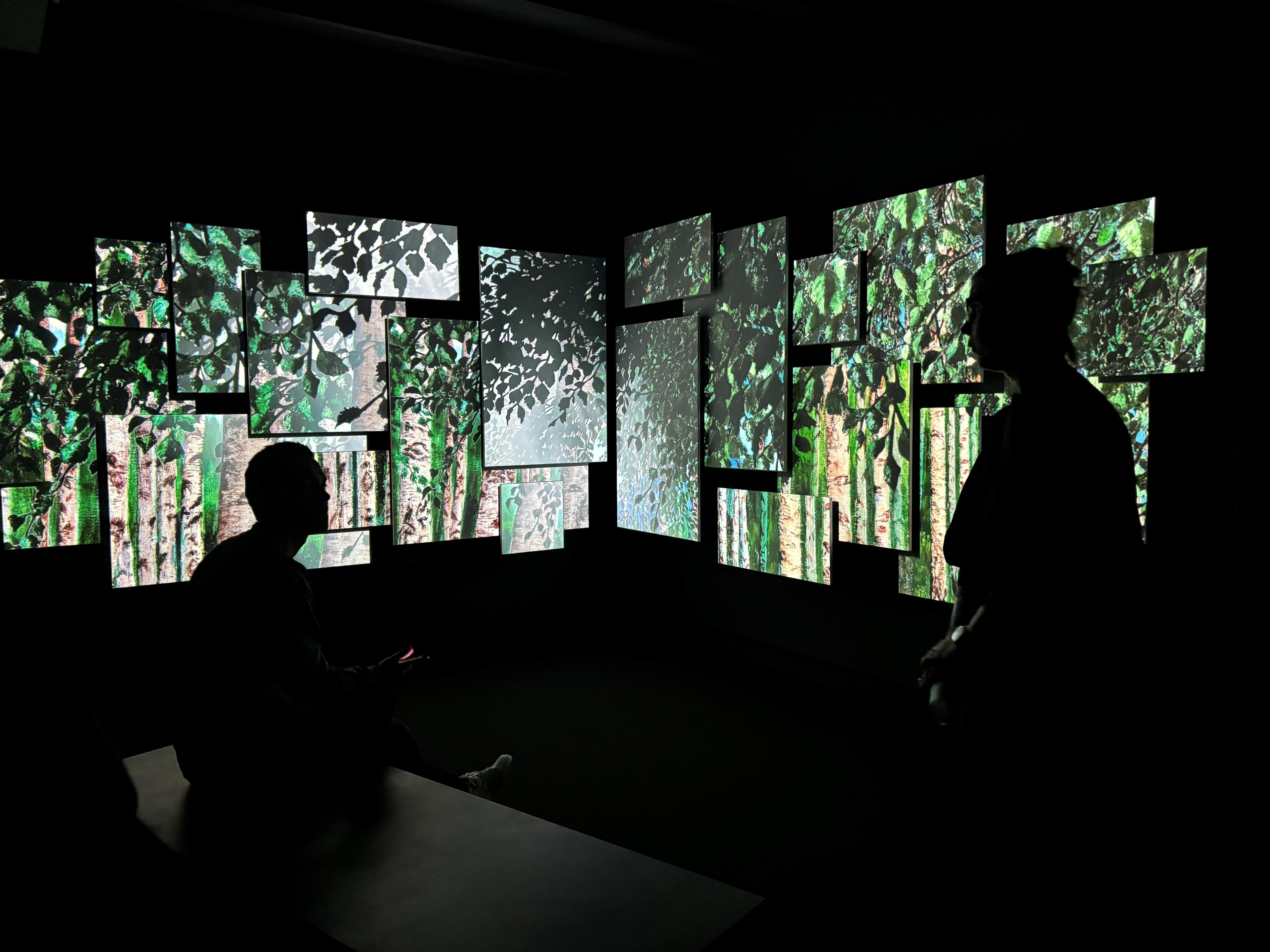 To mennesker inne i en digital multimediainstallasjon med motiver av Astrup.