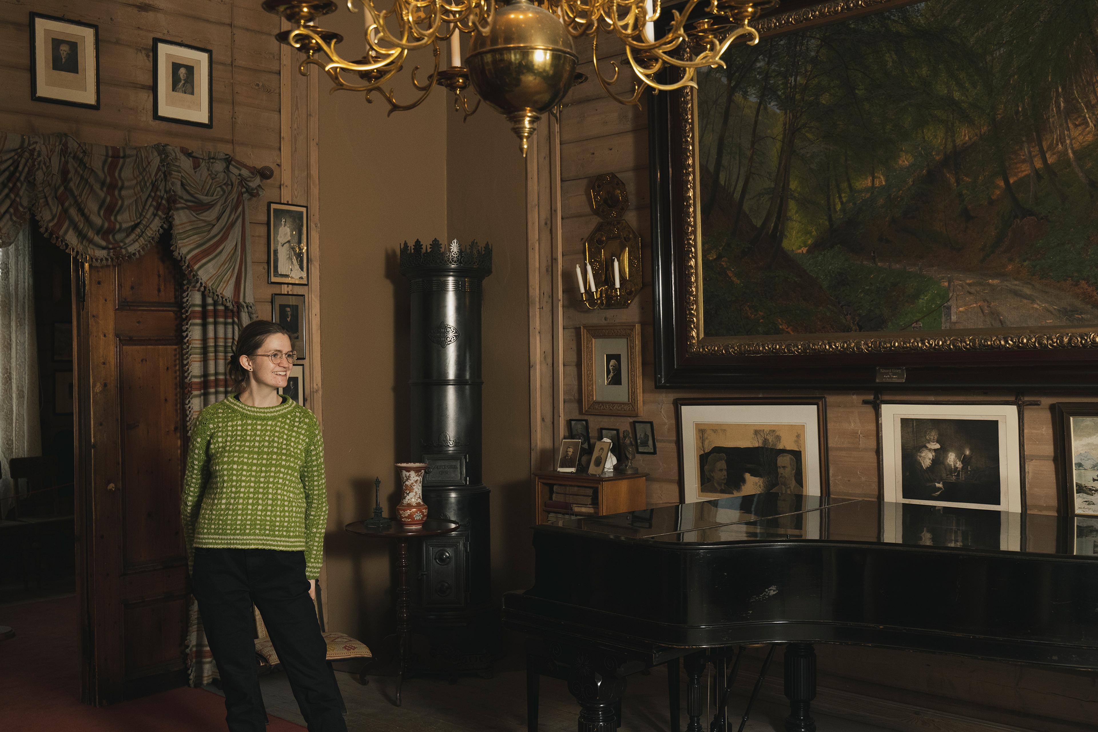 A museum guide in the villa. She is standing by the large piano.