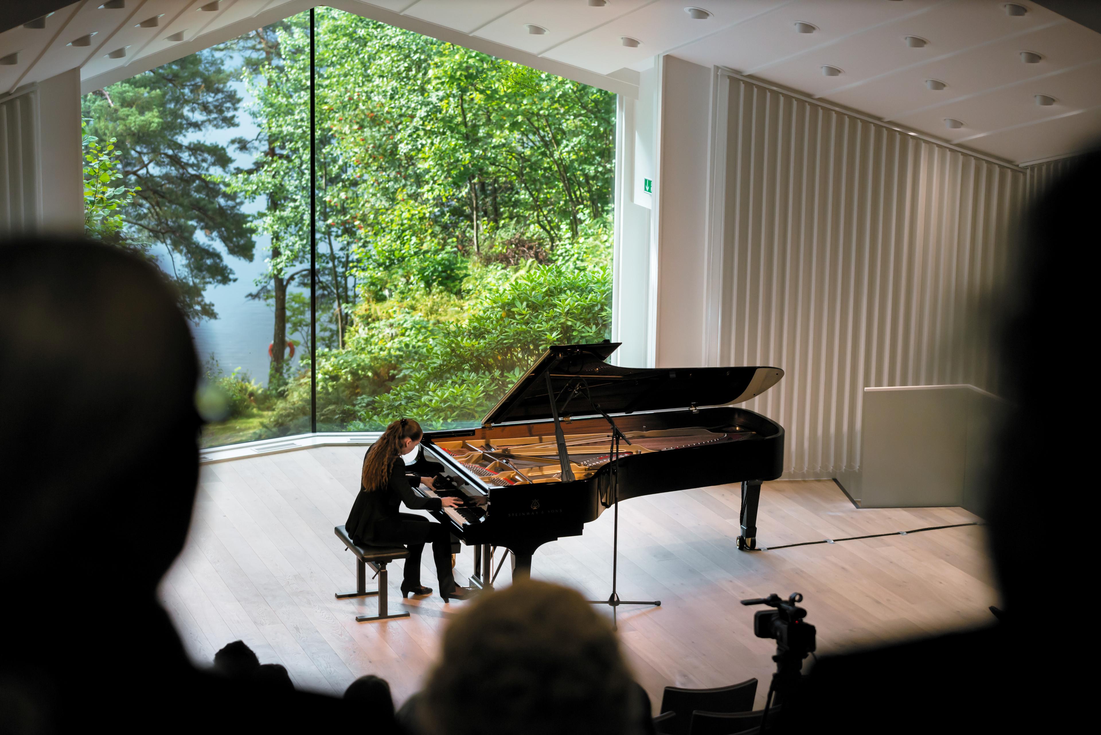 A pianist performing in the concert hall, with audience in the front