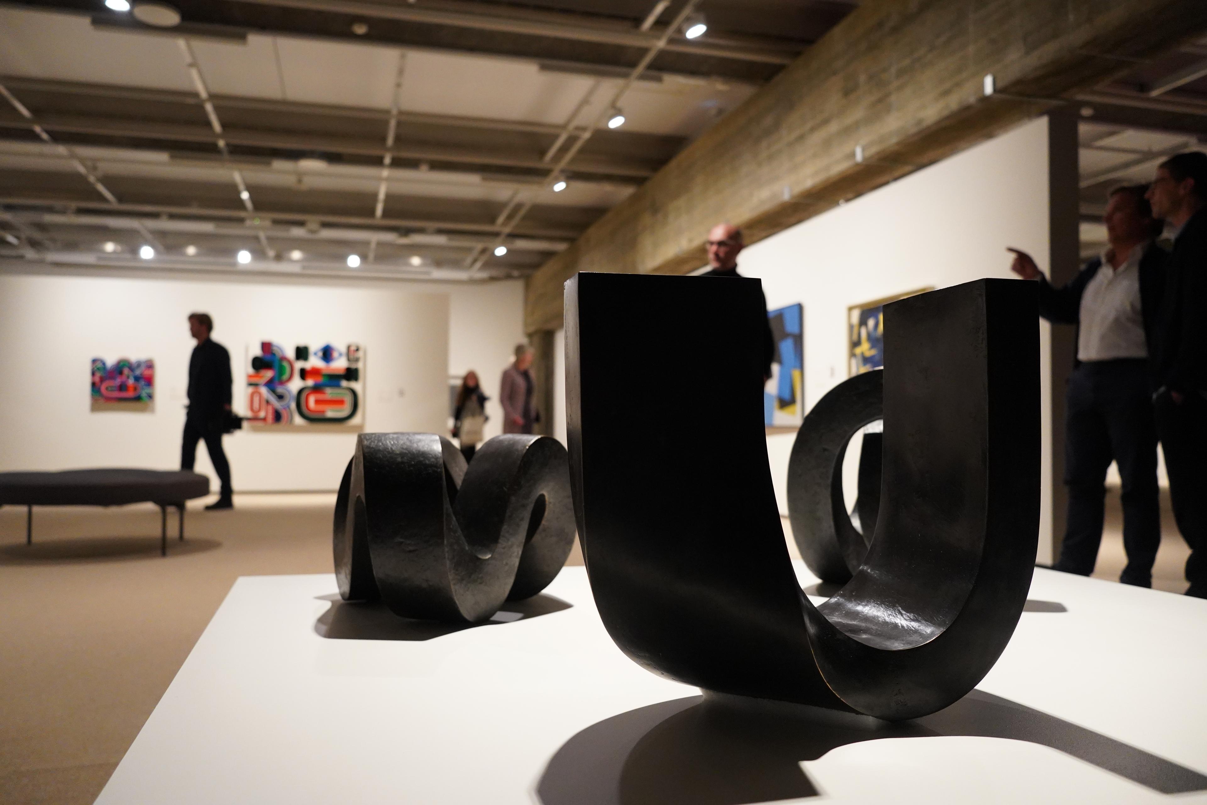 Et utstillingsrom med abstrakte skulpturer i forgrunnen og bak abstrakte malerier, som henger på en hvit utstillingsvegg