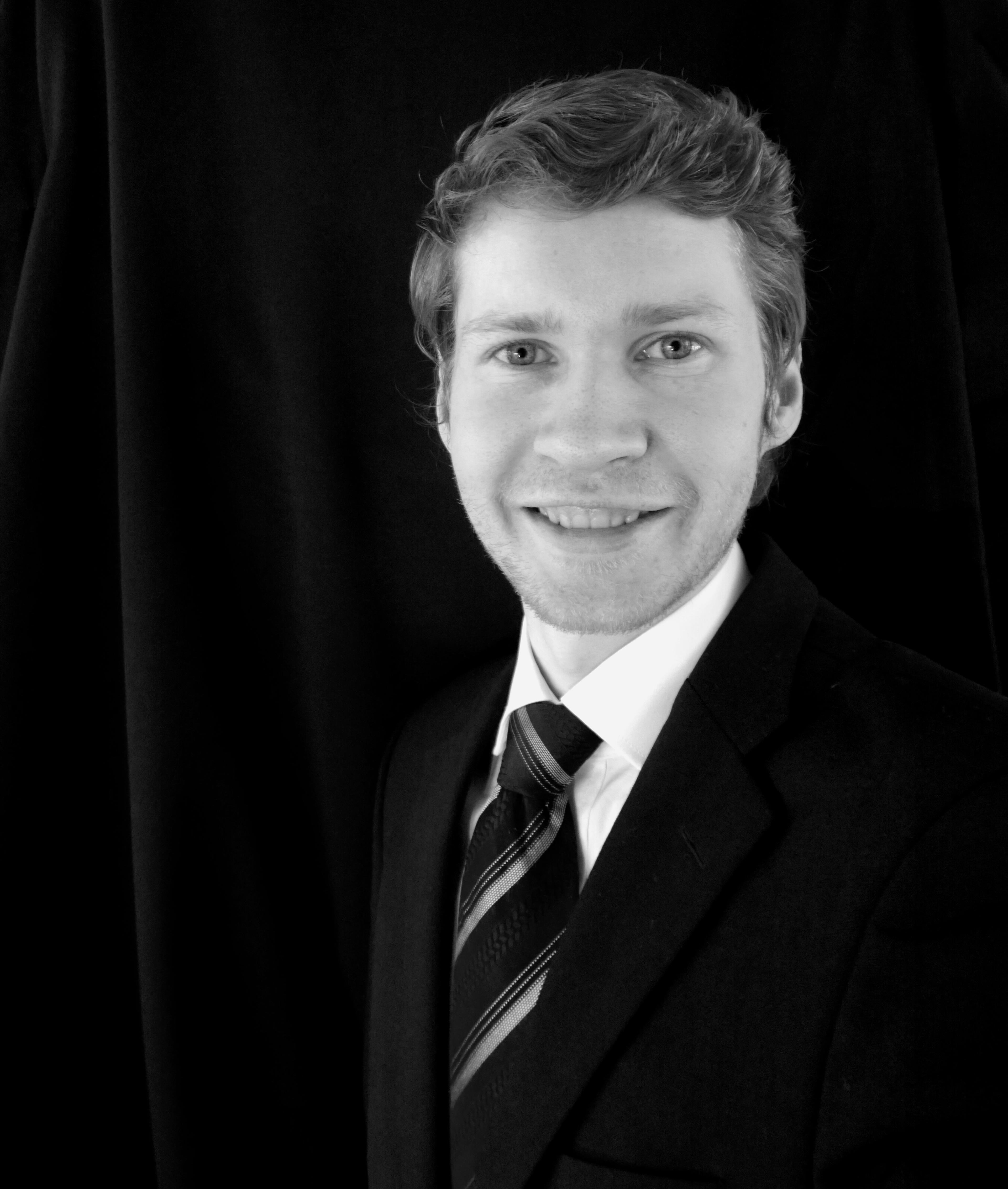 Et portrett av pianist Jørn Skauge som ser rett i kamera og smiler, ikledt en sort dress med slips.