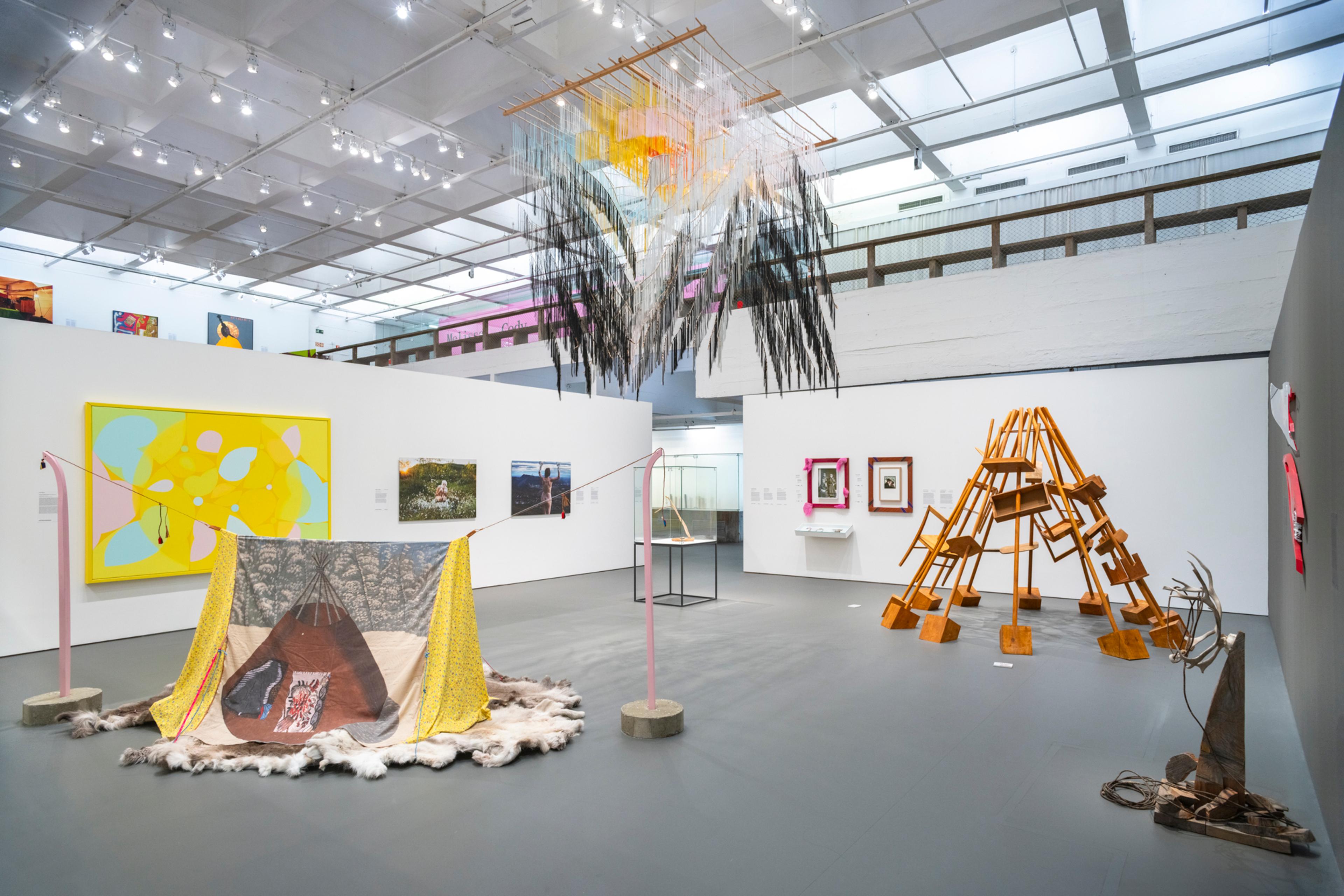 Et utstillingsrom med en rekke fargerike verk og objekter med samisk tilhørighet