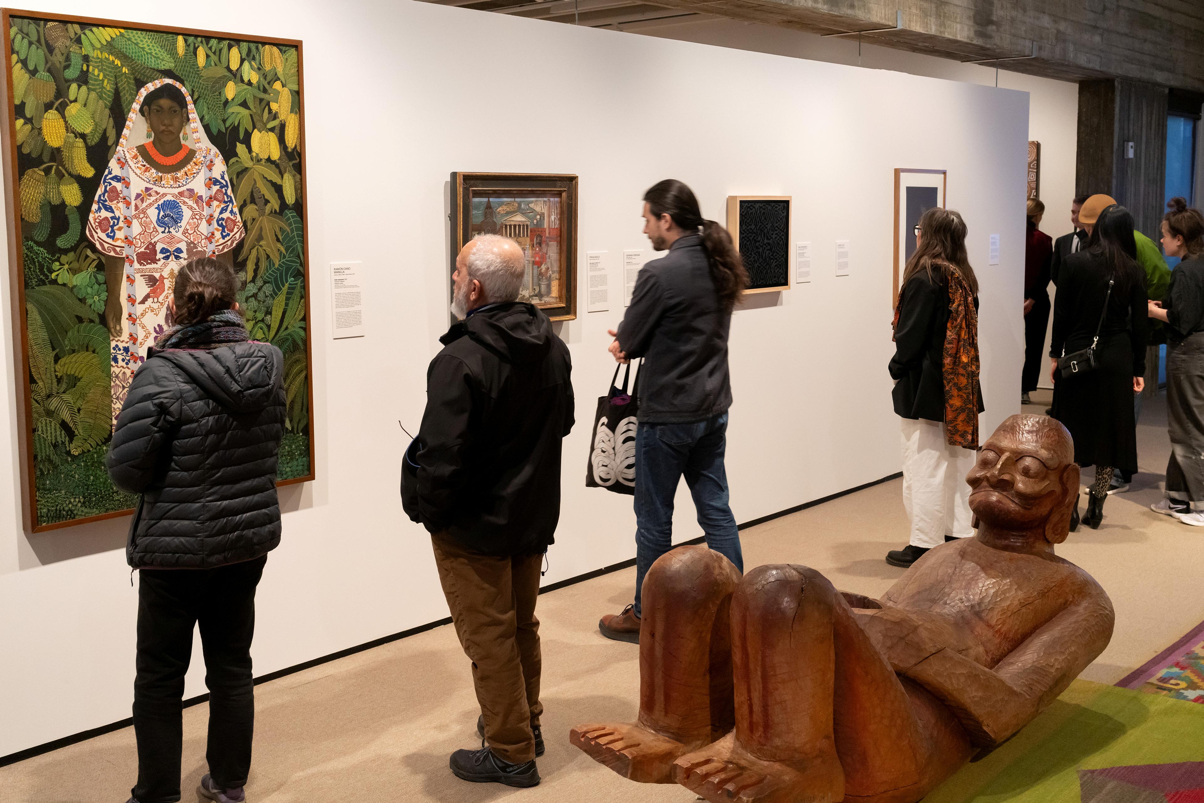 Folk foran en rekke kunstverk med en stor skulptur liggende på gulvet