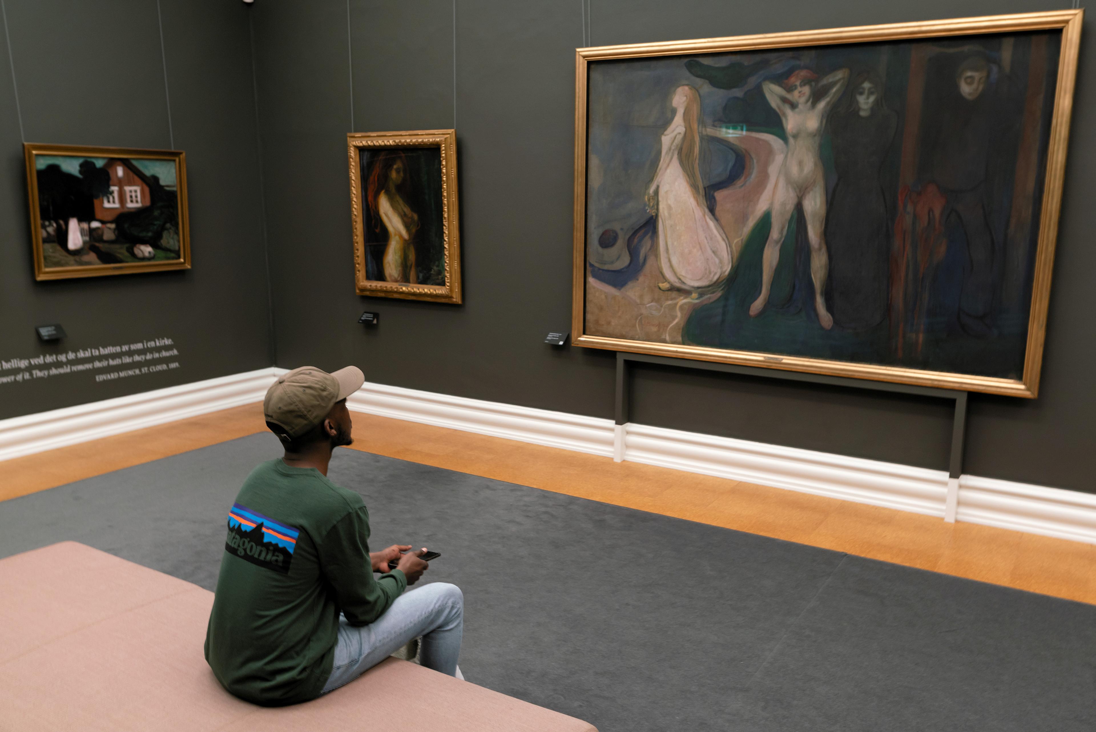 En ung mann sitter foran et maleri av Edvard Munch