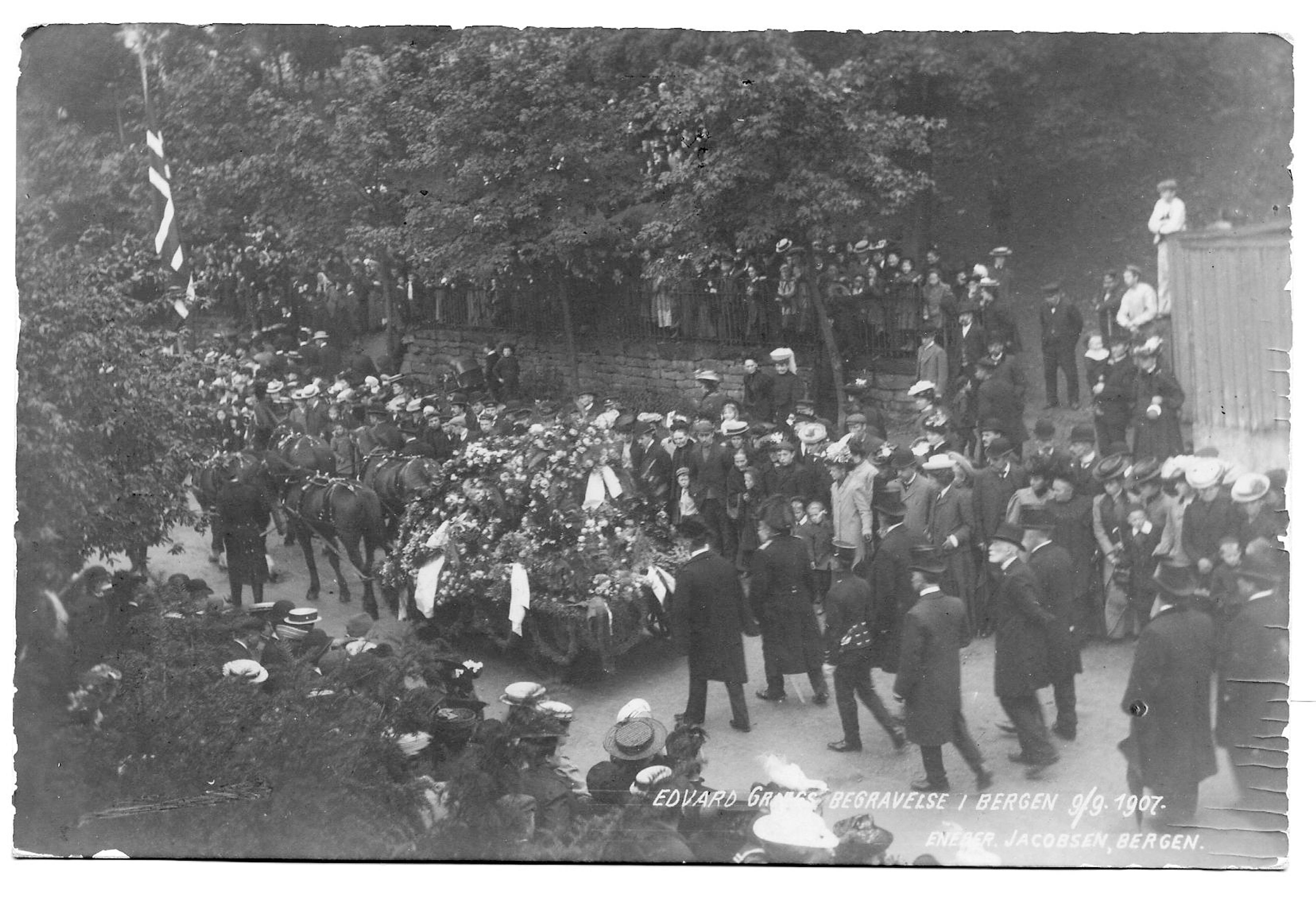 Fra Edvard Griegs begravelsesprosesjon gjennom Bergens gater, bilde av kisten på hestevogn og en stor folkemengde.