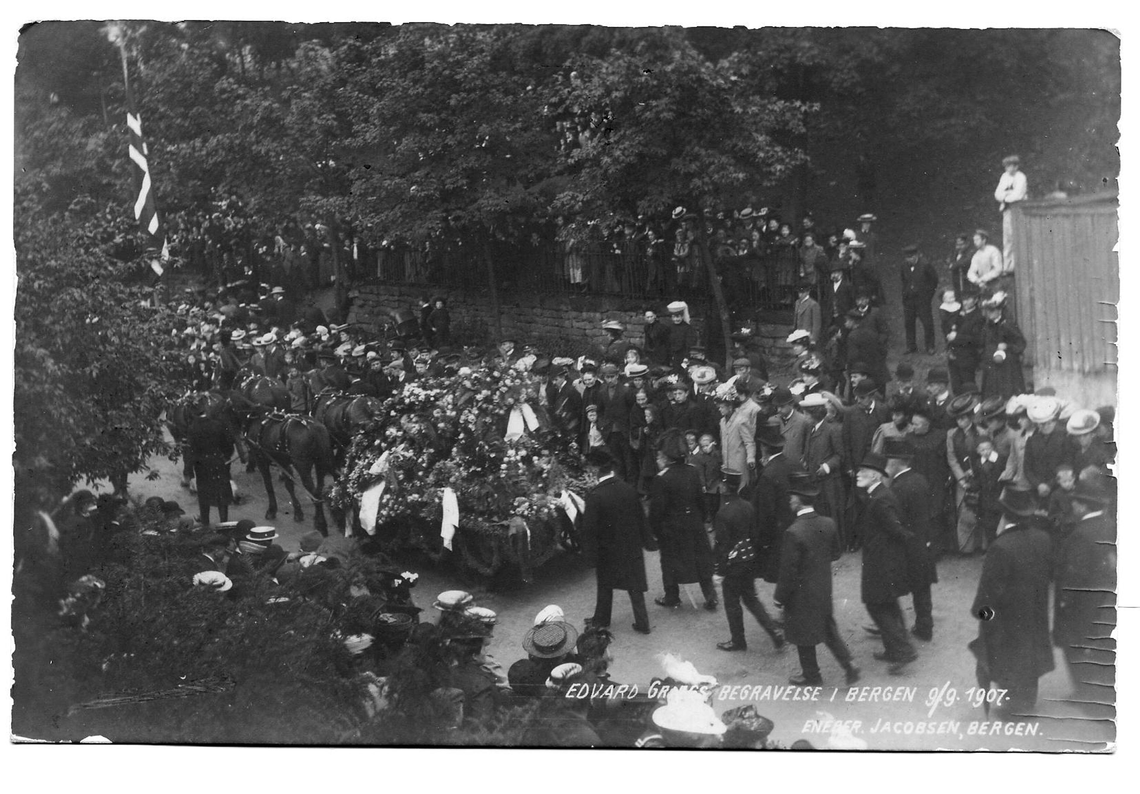 Fra Edvard Griegs begravelsesprosesjon gjennom Bergens gater, bilde av kisten på hestevogn og en stor folkemengde.