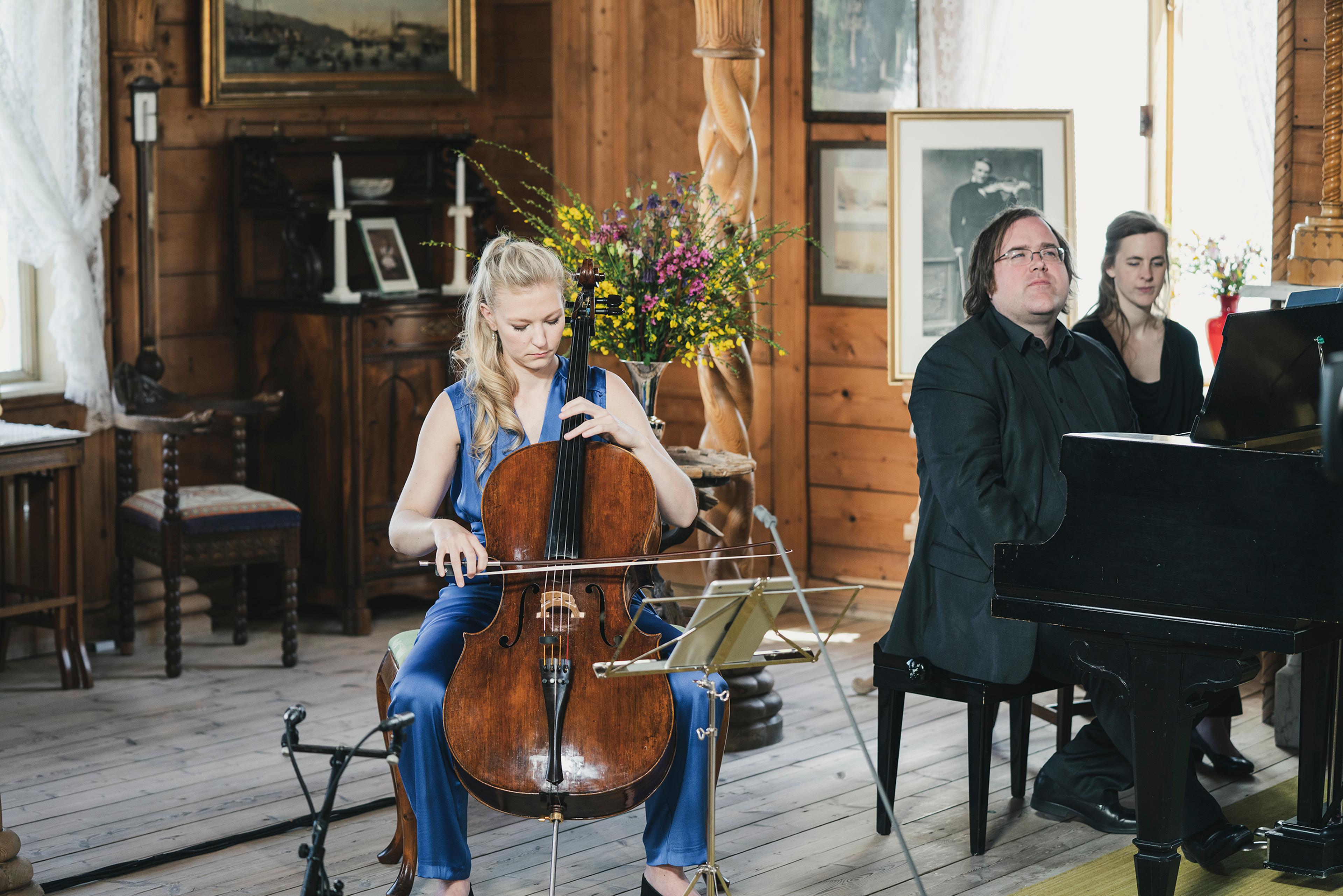 En kvinne som spiller på cello foran to personer ved et piano, i konserthallen på Lysøen