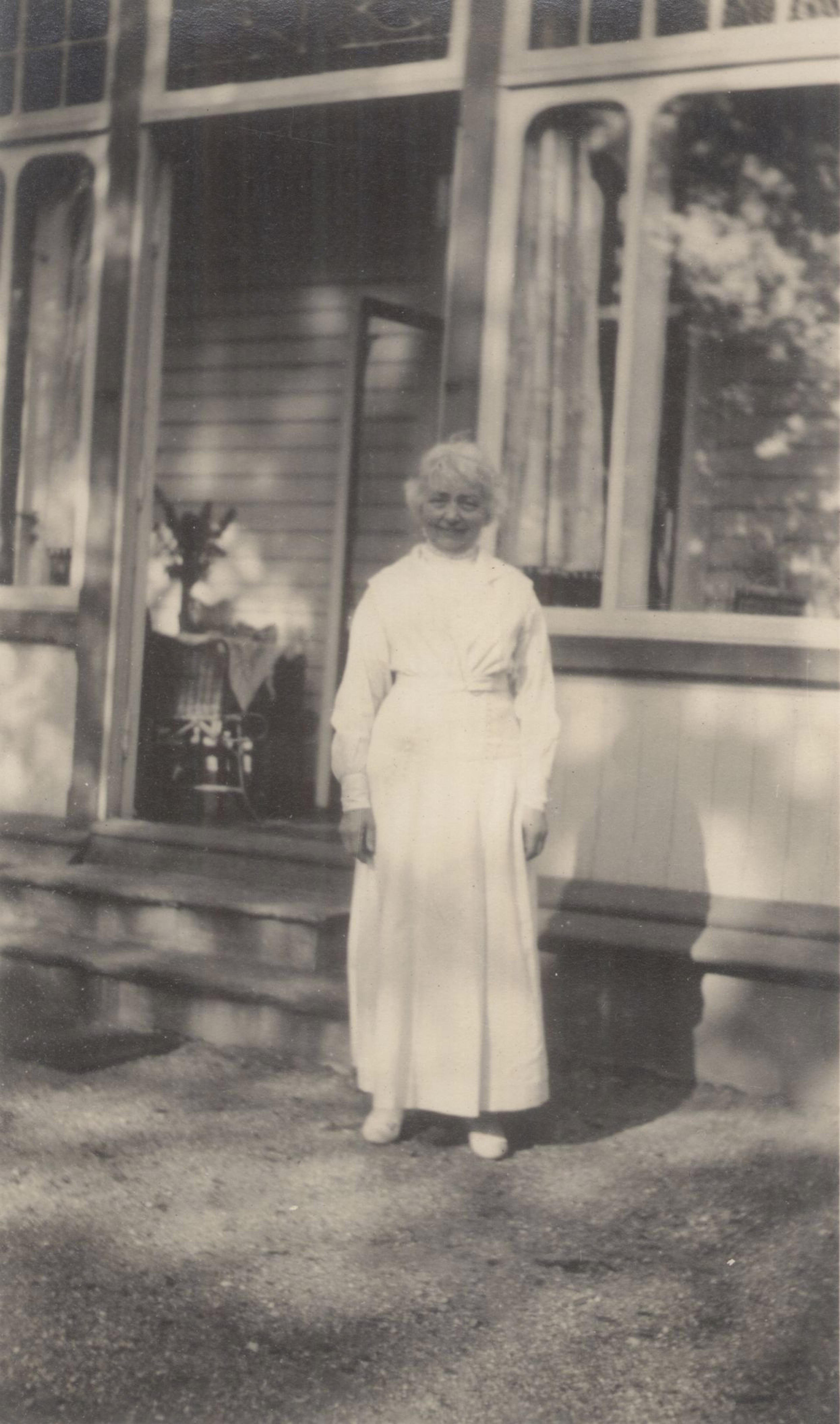 Fotografi av den eldre Nina Grieg utenfor villaen på Troldhaugen. 