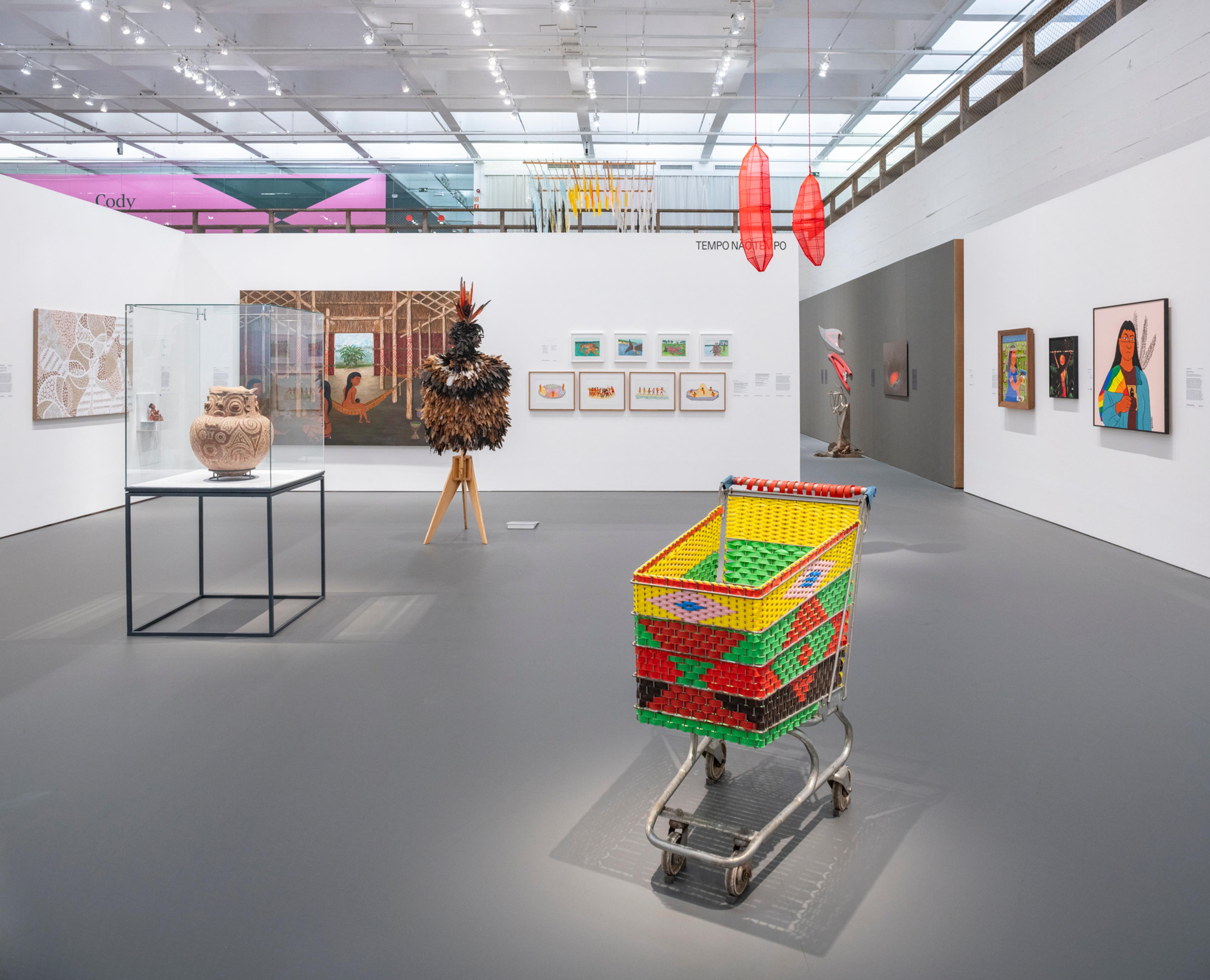 An exhibition room with white walls, presenting a range of colorful objects, images and paintings