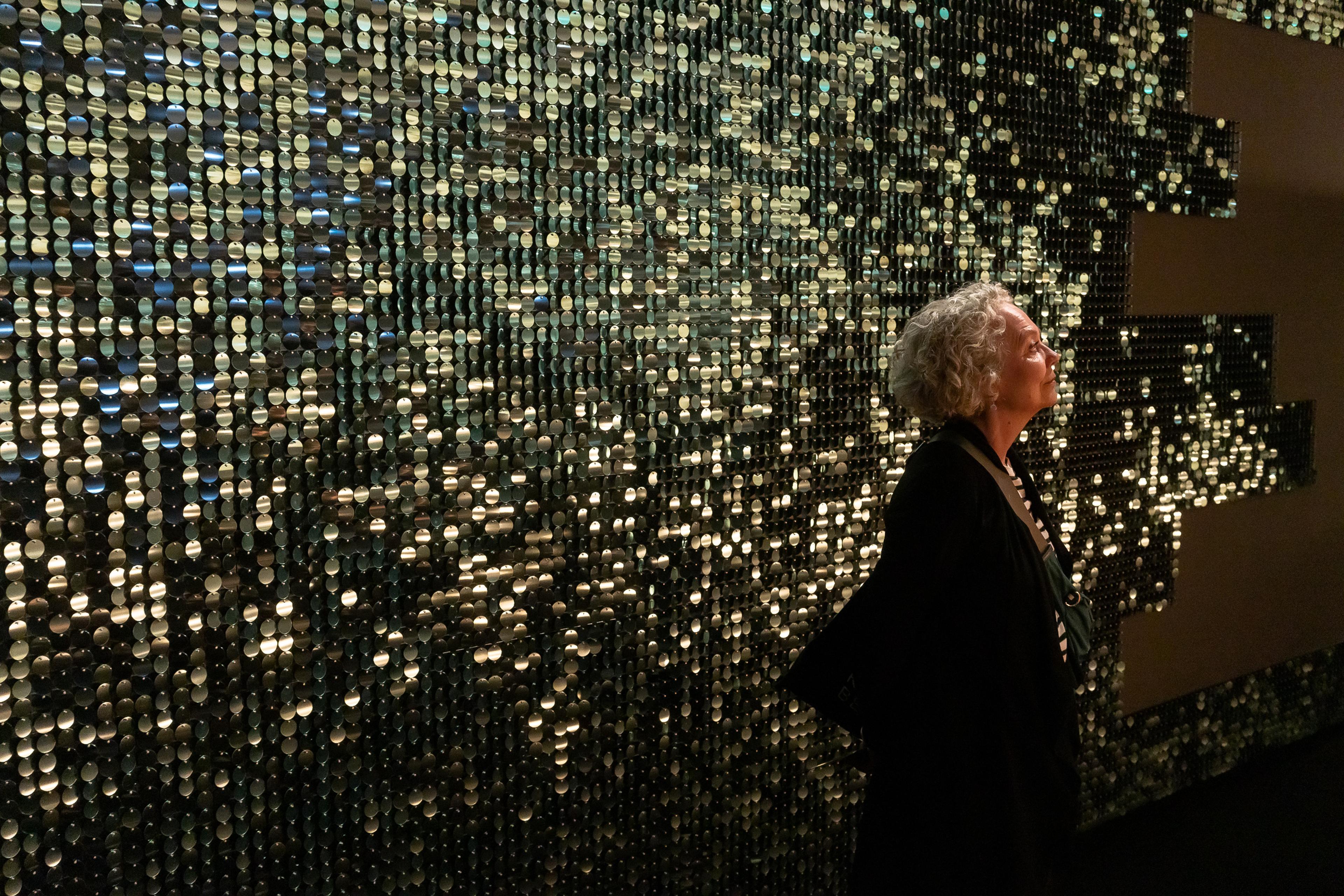 En kvinne står foran en vegg dekket av paljettpaneler