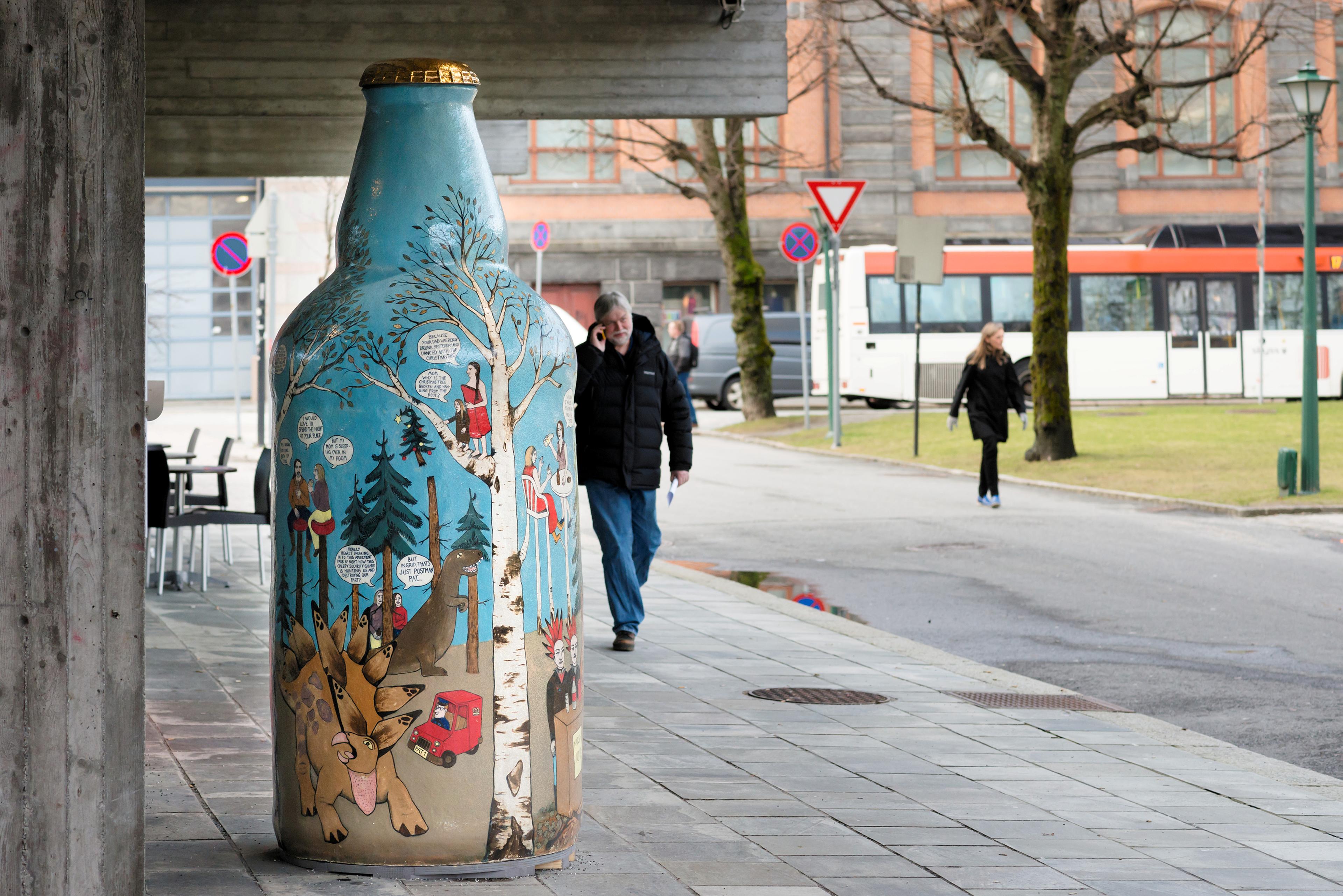 En stor keramikkskulptur i form av en ølflaske med tegneserieaktig dekor vist utendørs i Bergen