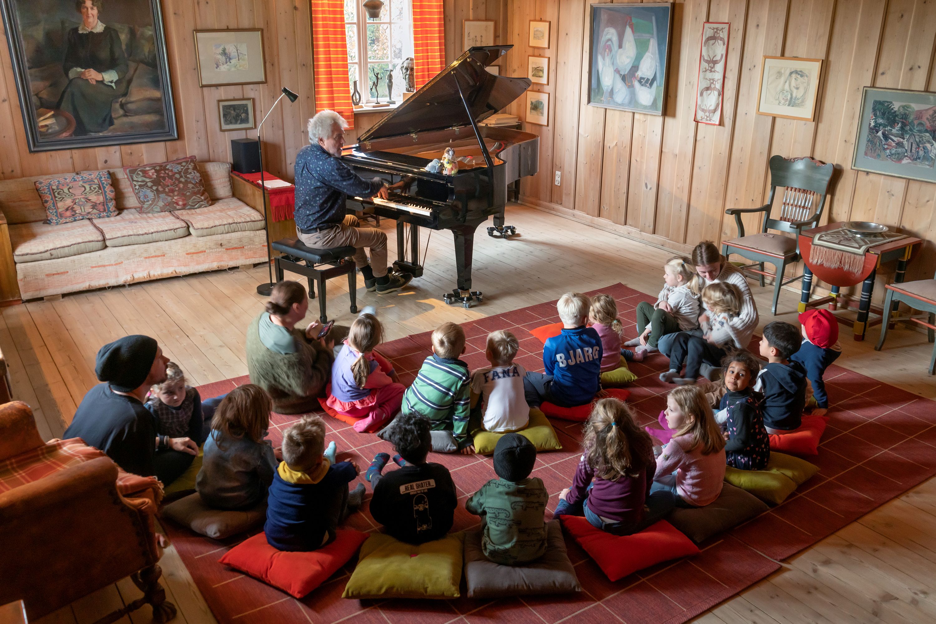En gruppe barn som ser på en person som spiller piano