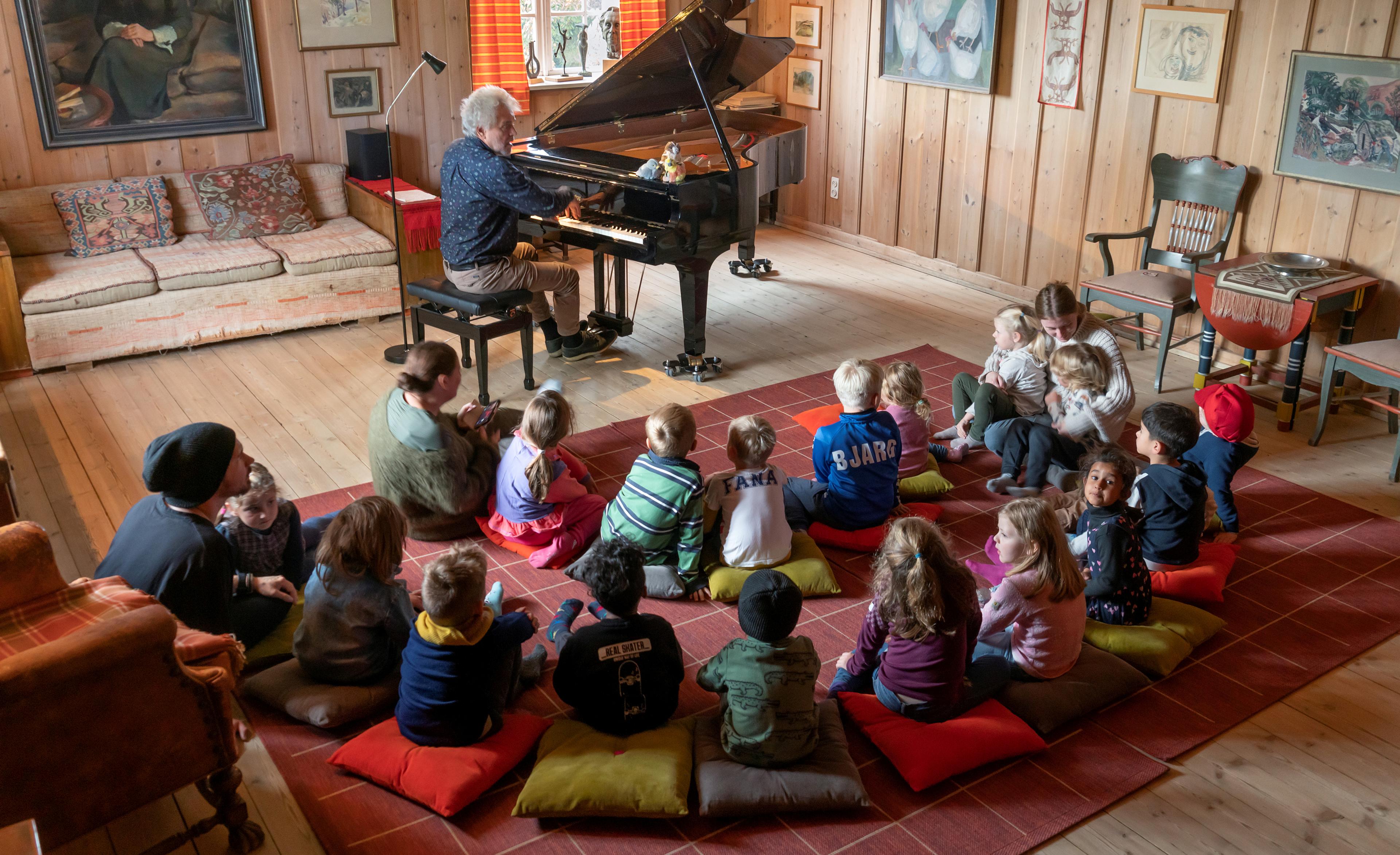 En gruppe barn som ser på en person som spiller piano