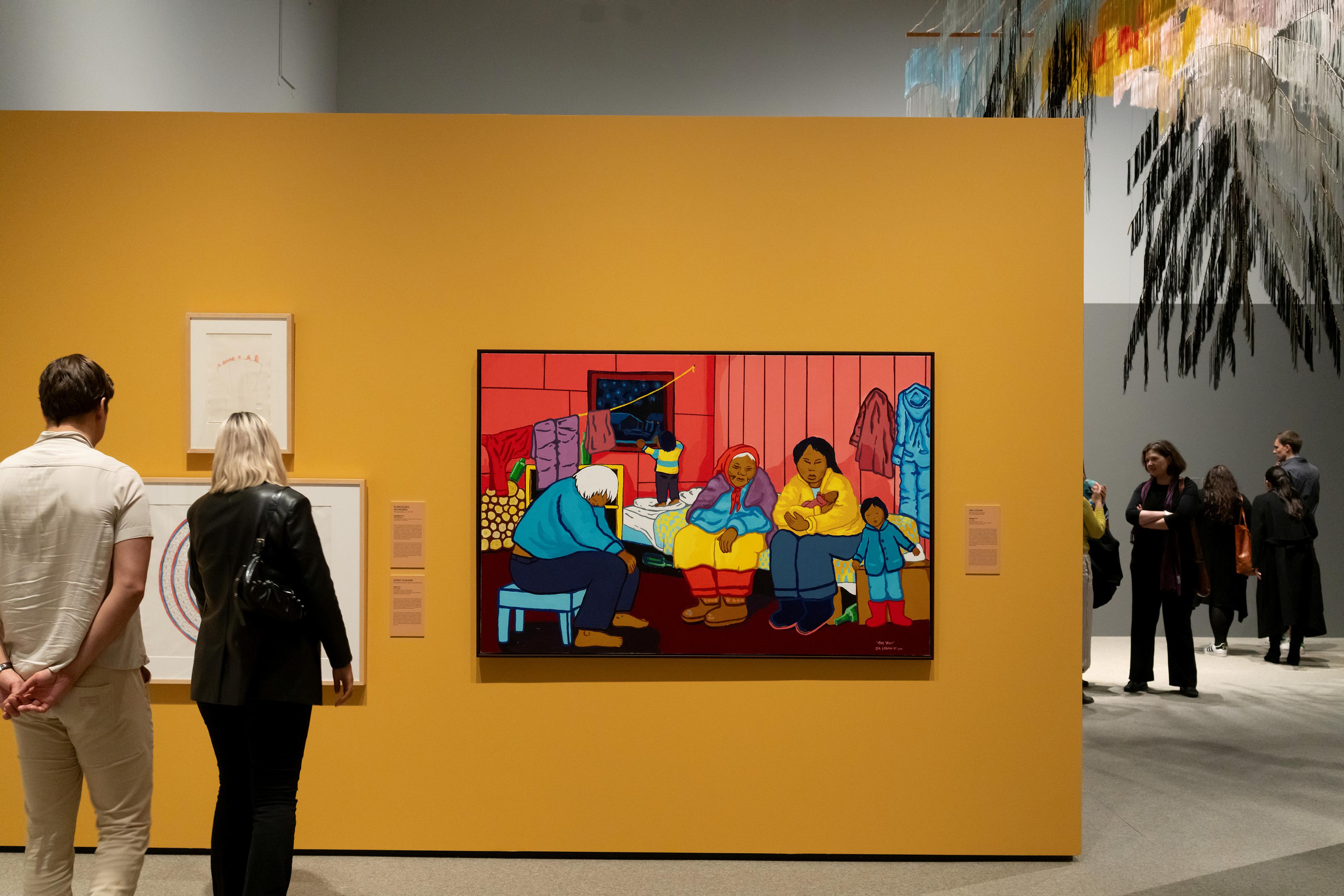 To personer foran et maleri, mot en gul vegg, i en utstillingssal