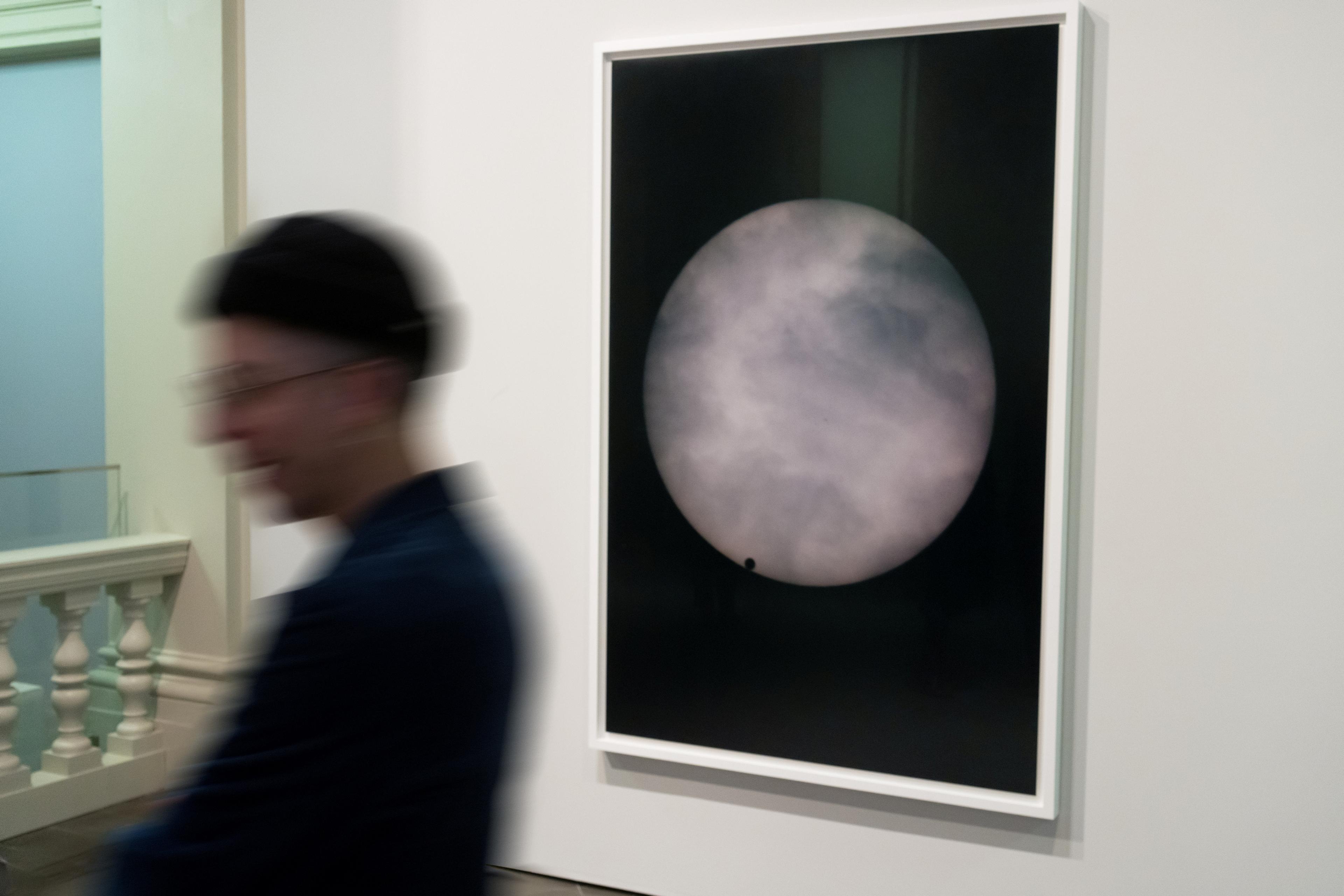 A man in front of an artwork depicting a moon