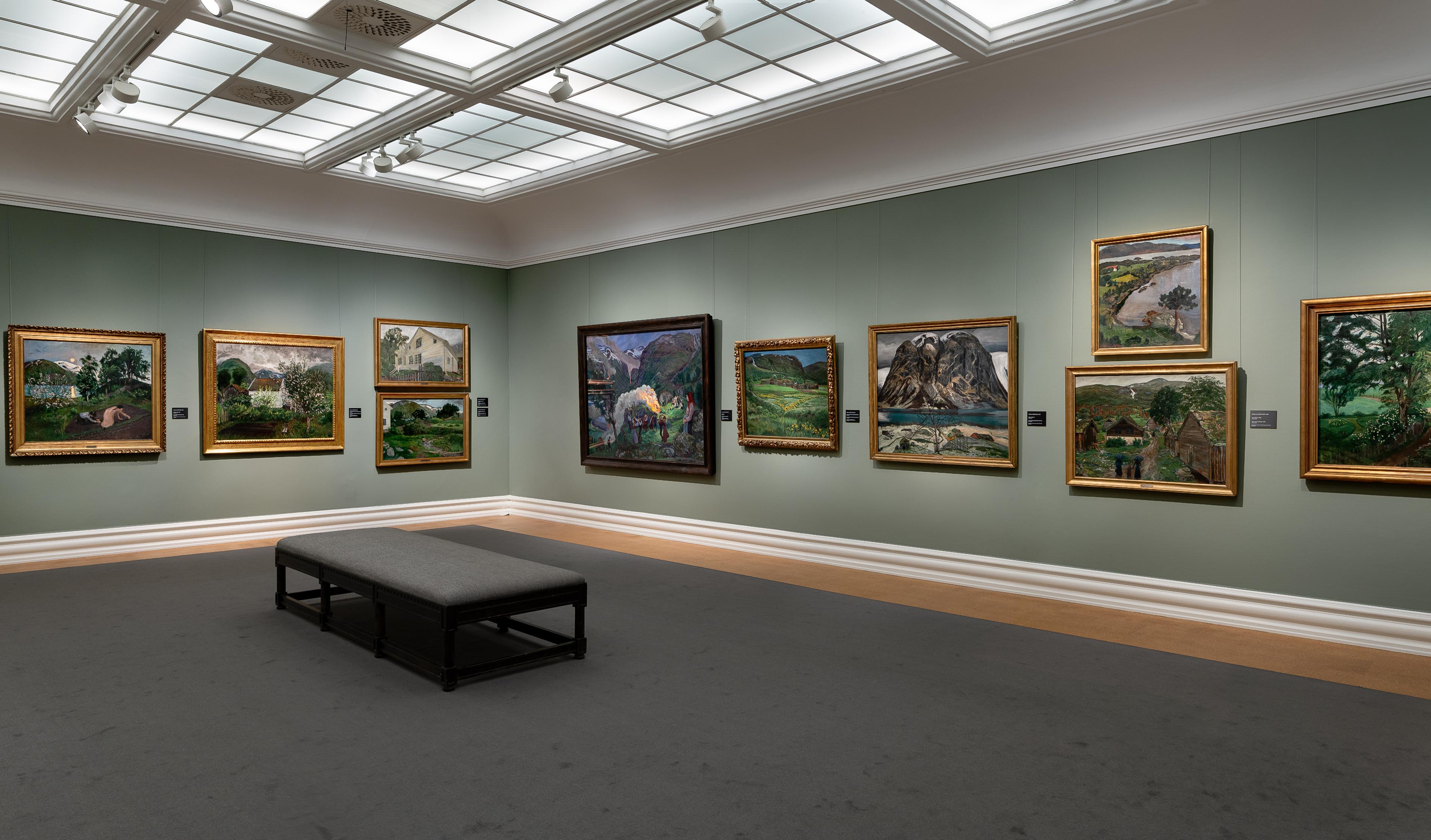 En utstillingssal med lysgrønne vegger og malerier av Nikolai Astrup