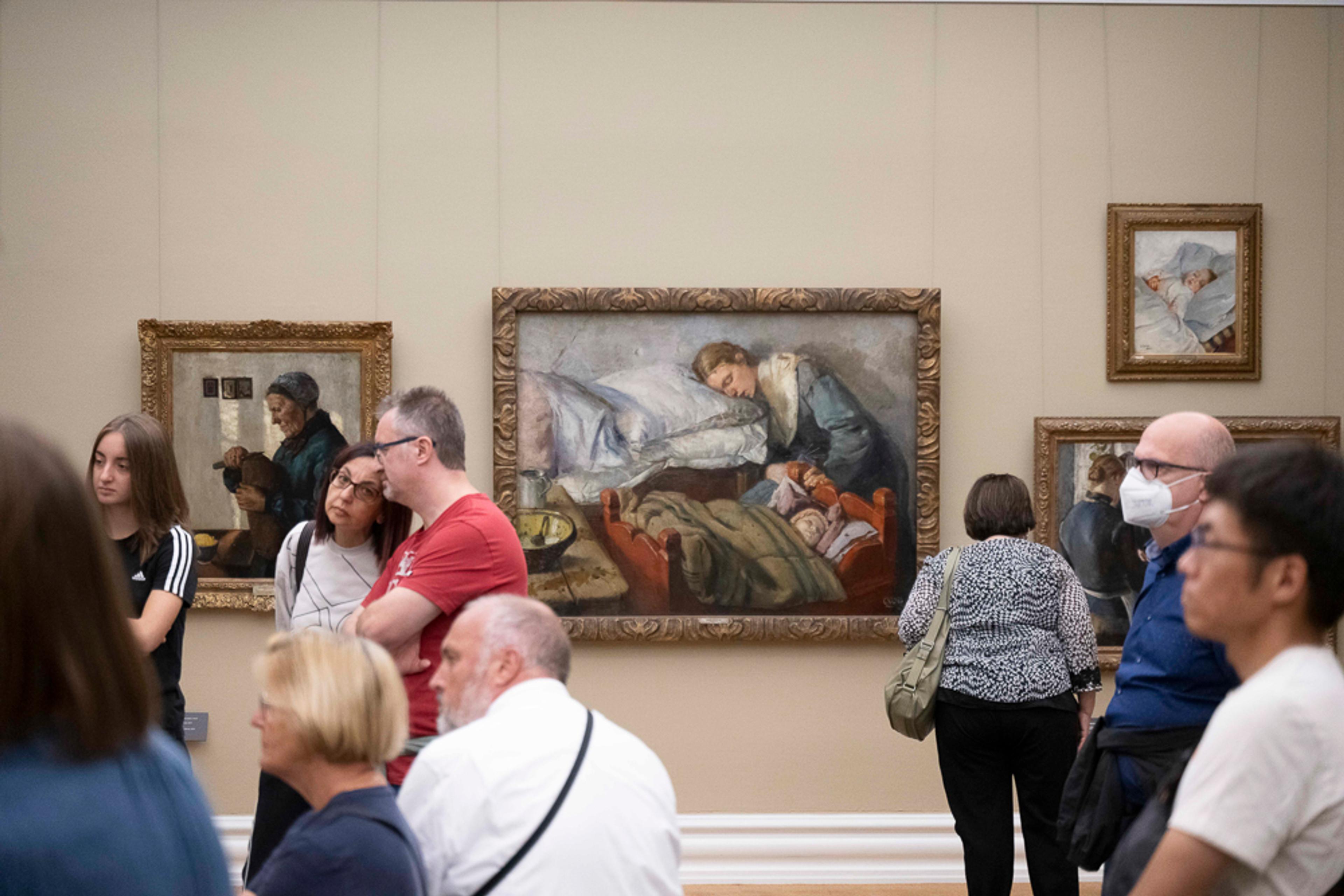 Fotografi av en gruppe mennesker som ser på malerier i ramme på vegg, inne i Rasmus Meyers samlinger.
