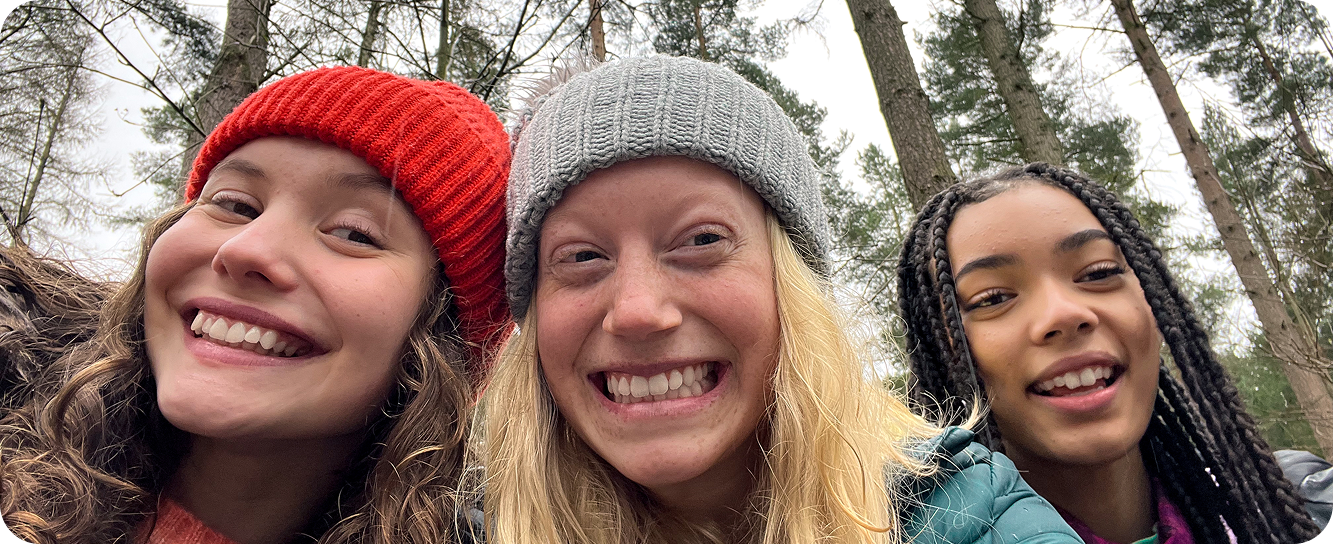 Three smiling children in the woods