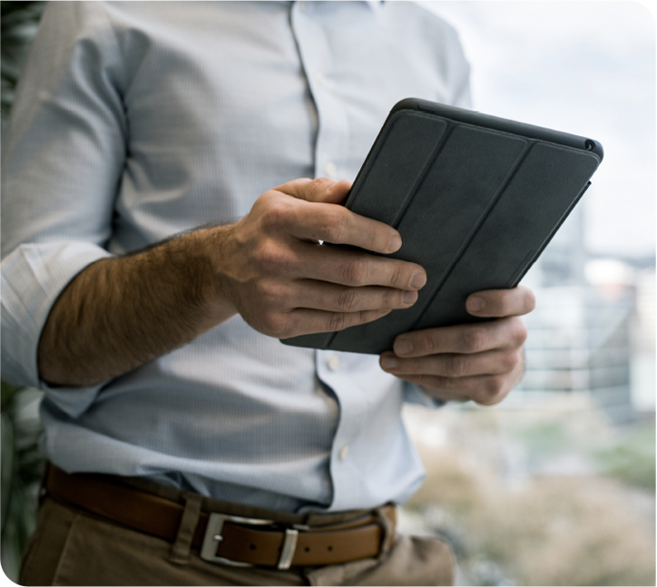 A person in a dress shirt holding a tablet in a folio case.