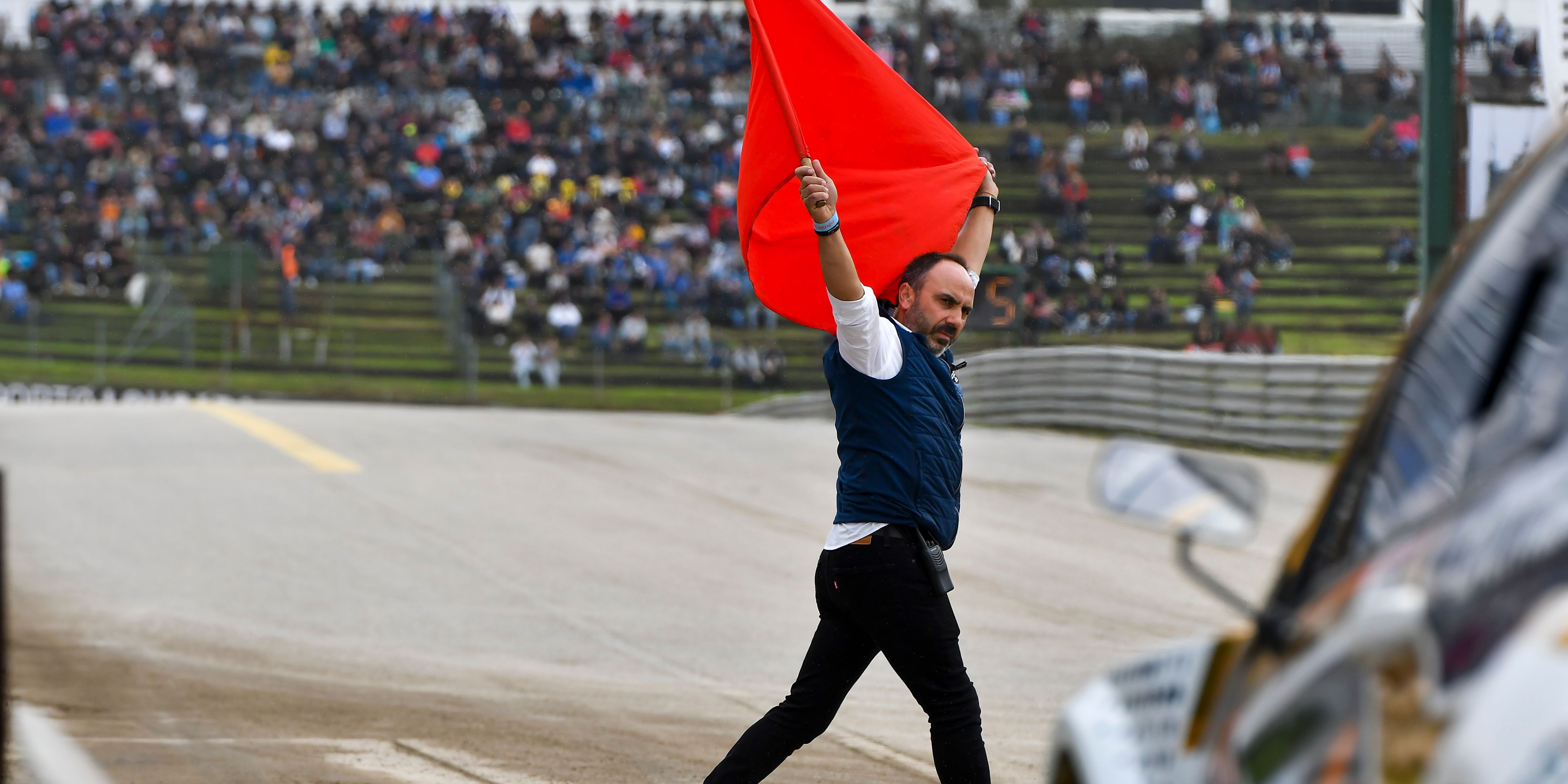a man is holding a red flag on a race track .