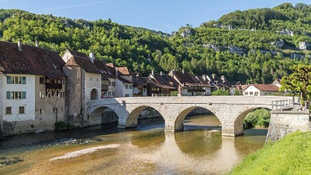 Arched stone Doubs Bridge and old town houses in St. Ursanne, Canton Jura, Switzerland