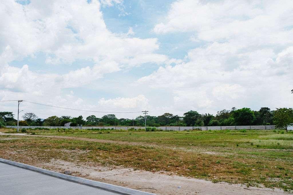 Terreno vazio e muro de divisa em Ciudad Morazán, à espera de desenvolvimento após a paralisação das obras