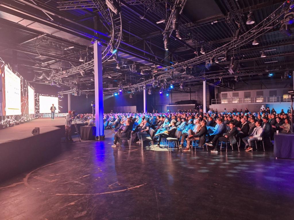 Wide view of the seated audience in the industrial hall of the Network State Conference in Amsterdam