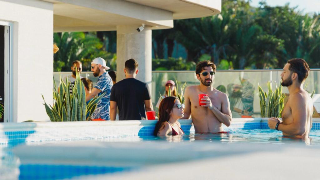 Guests with drinks relaxing in the rooftop pool of Duna Tower in Próspera, Roatán