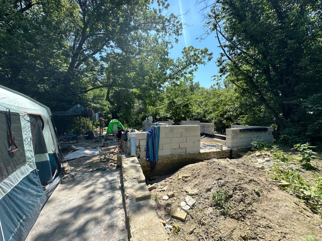 Concrete block walls rising beside tents at the Jefferson Square construction site in Liberland
