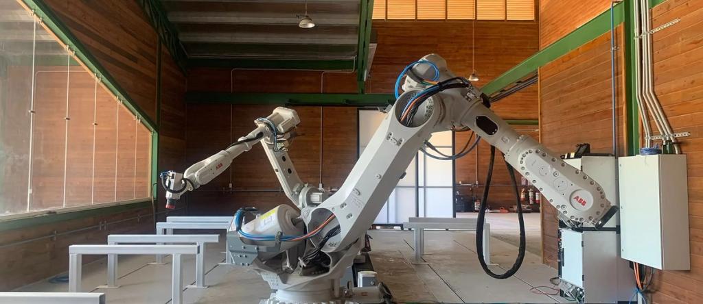 Large ABB industrial robot arm inside a timber-walled factory hall for automated construction