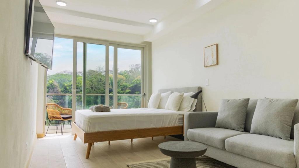Bright studio apartment in Duna Tower, Próspera, with bed, sofa and balcony facing the jungle