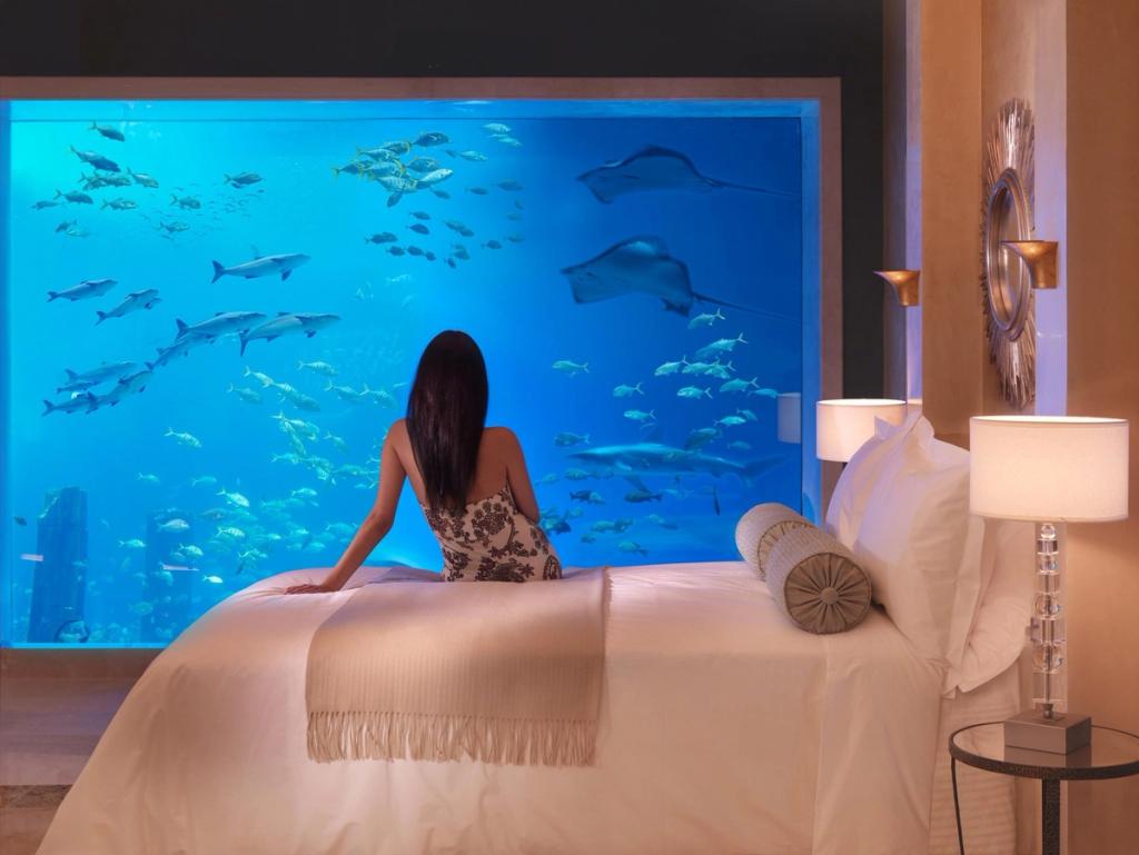 Huésped en la Atlantis Underwater Suite de Palm Jumeirah, Dubái, frente a un acuario con mantarrayas y peces