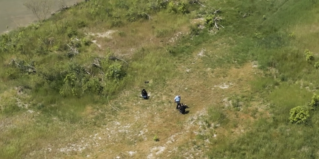 Drone shot of a Croatian policeman assaulting videomakers on a grassy island in Liberland