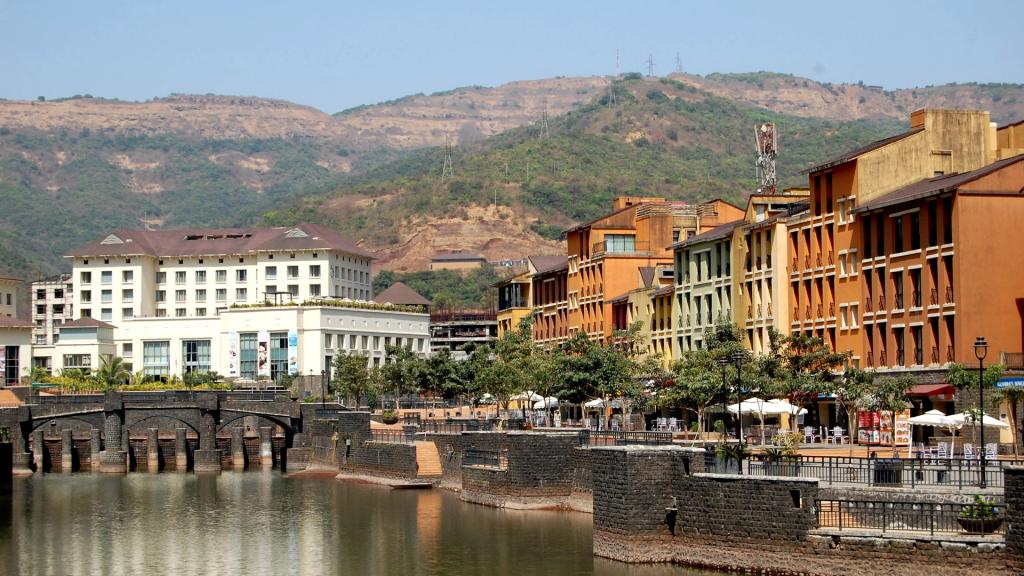 Lakeside promenade with pastel buildings and green hills in Lavasa, India's private city