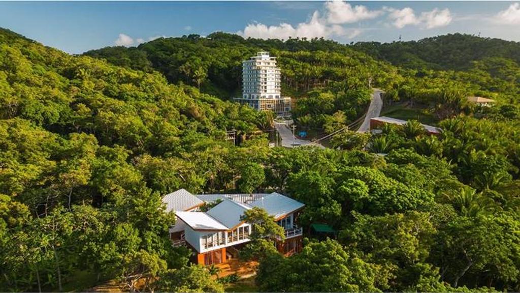Aerial view of the Beta district in Próspera, Roatán, with a residential tower and villas in tropical forest
